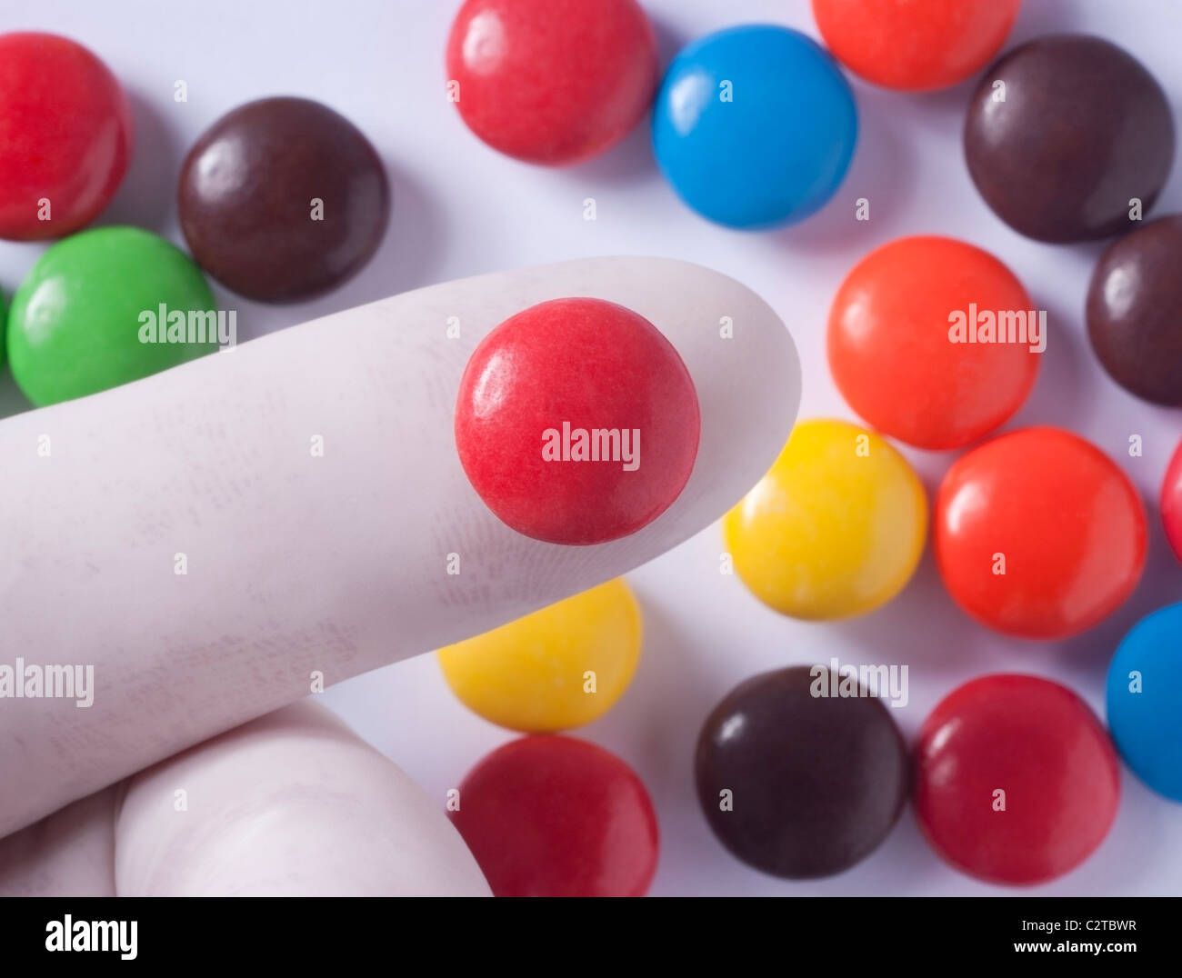 Gloved finger holding candy sold in the United States that contains