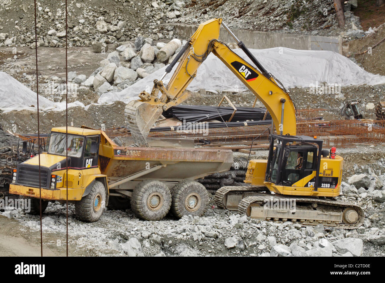 Excavator loading large rocks onto huge dump truck on construction site ...