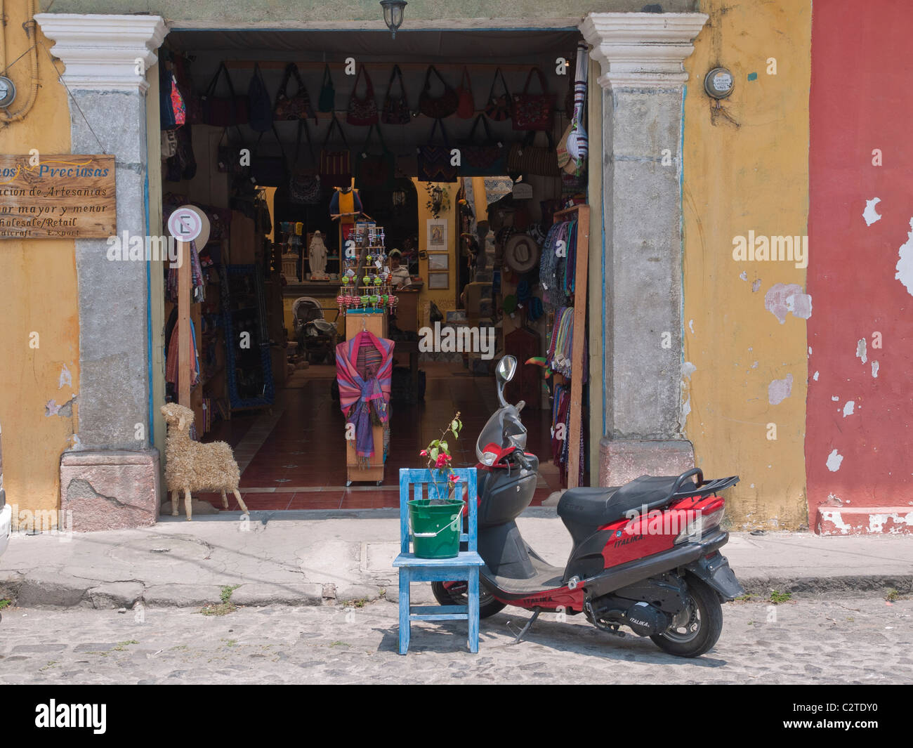 A red and black motor scooter and a blue chair sit in the street in