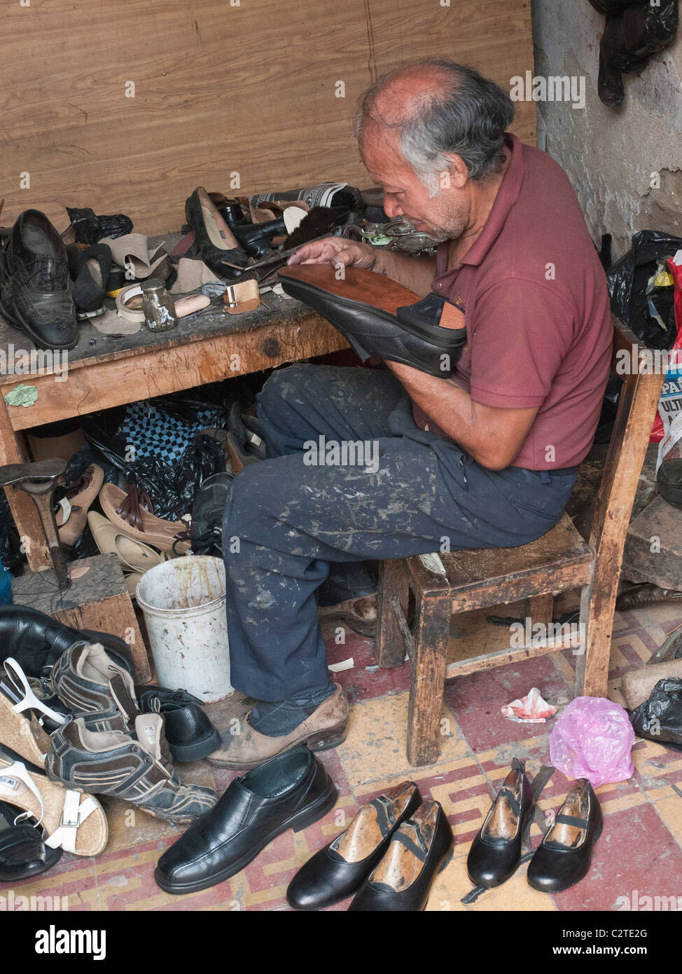 A cobbler works repairing a shoe in his shop on a side street in the city center in the Spanish colonial city of Antigua. Stock Photo