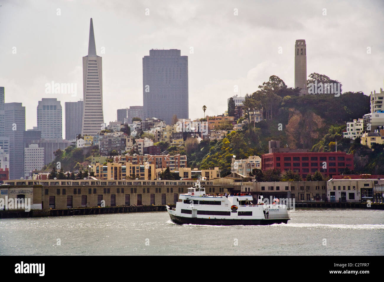 A tourist cruise boat to passes San Francisco's waterfront on the way to Alcatraz Island and its infamous prison. Note Transamer Stock Photo