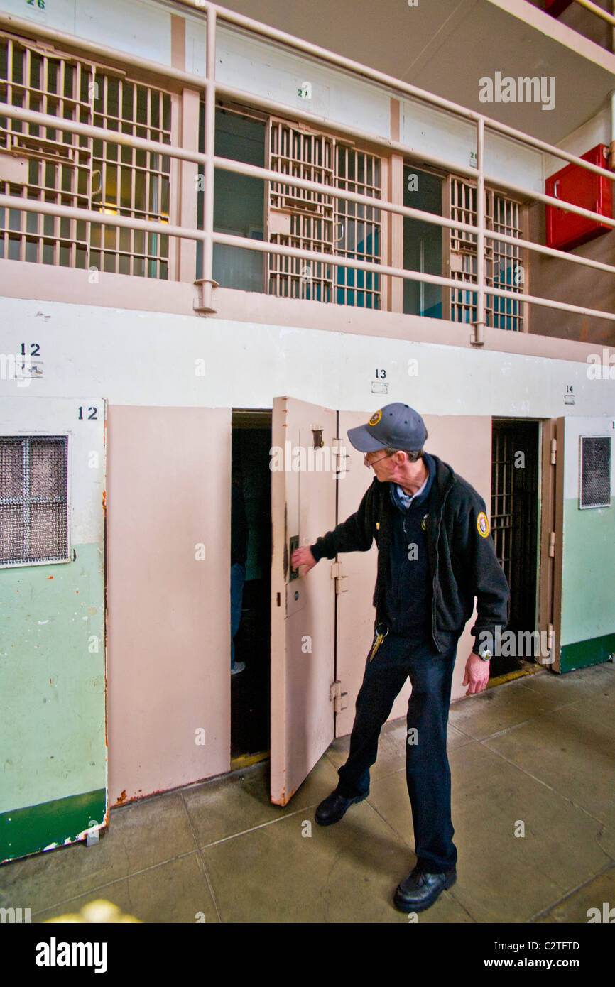 A uniformed volunteer opens the door of a solitary confinement cell to tourists in Cellblock D at the former Alcatraz Prison. Stock Photo