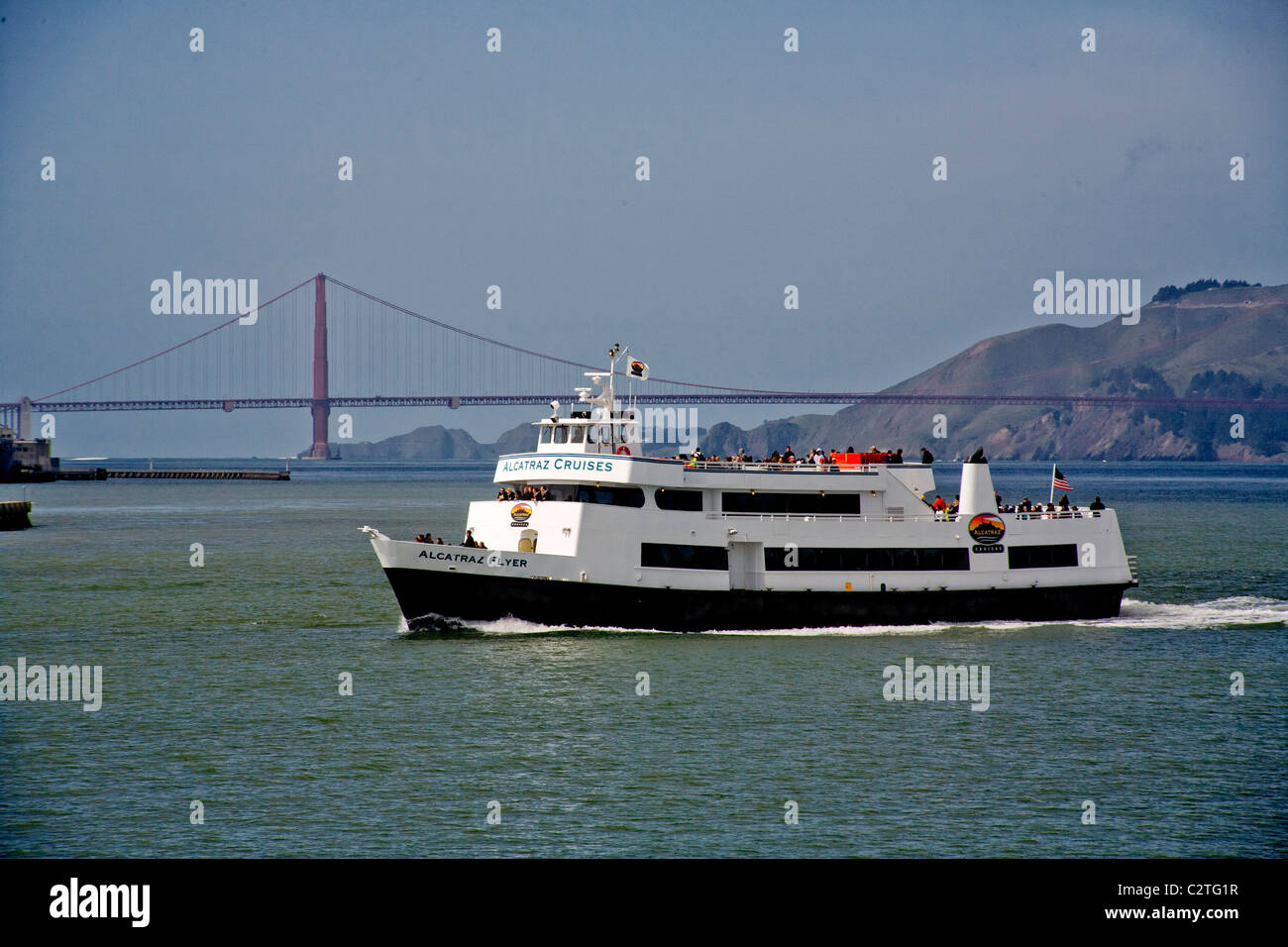 A tourist cruise boat to passes San Francisco's Oakland-Bay Bridge on the way to Alcatraz Island and its infamous prison. Stock Photo