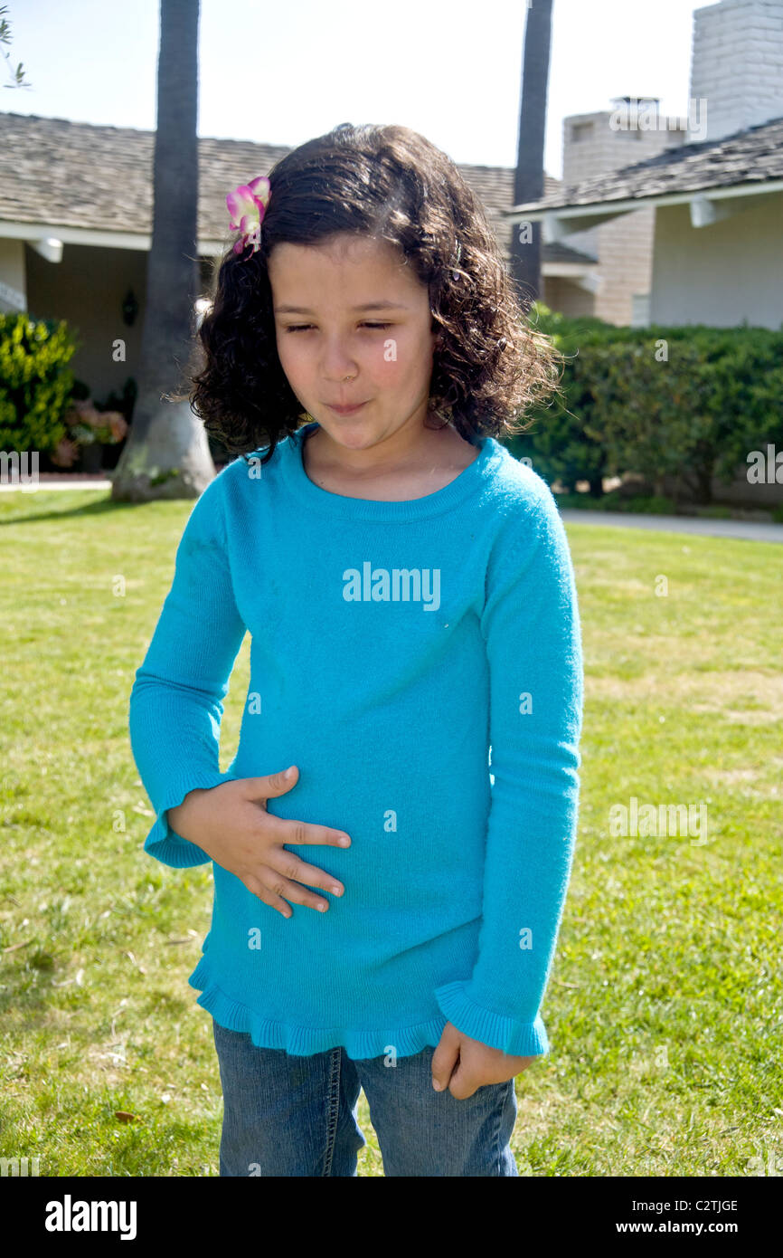 A five-year-old Egyptian-American girl winces with pain from a stomachache outdoors in Laguna Niguel, CA. Stock Photo