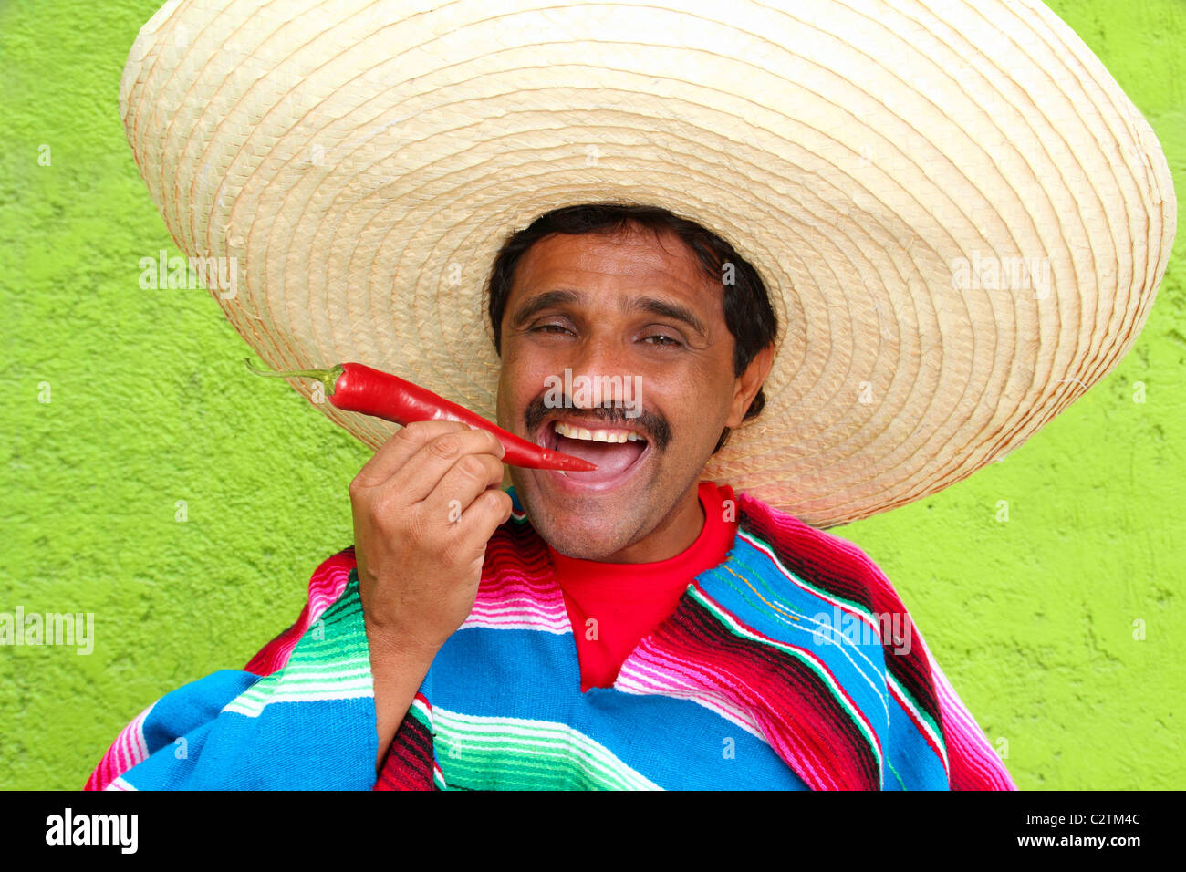 Mexican man poncho sombrero eating red chili hot pepper Mexico Stock ...