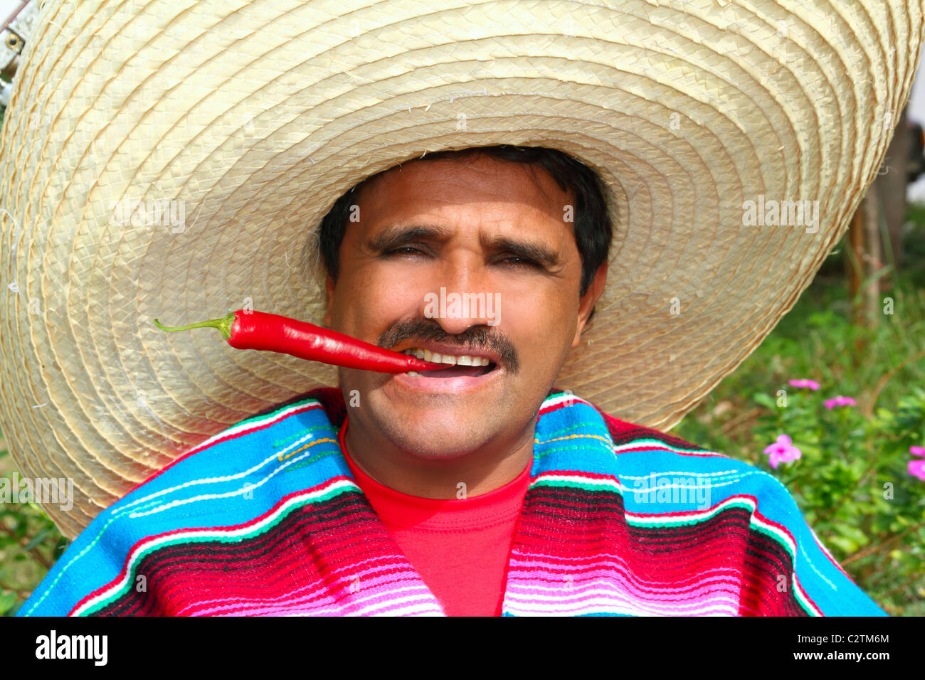 Mexican man poncho sombrero eating red chili hot pepper Mexico Stock