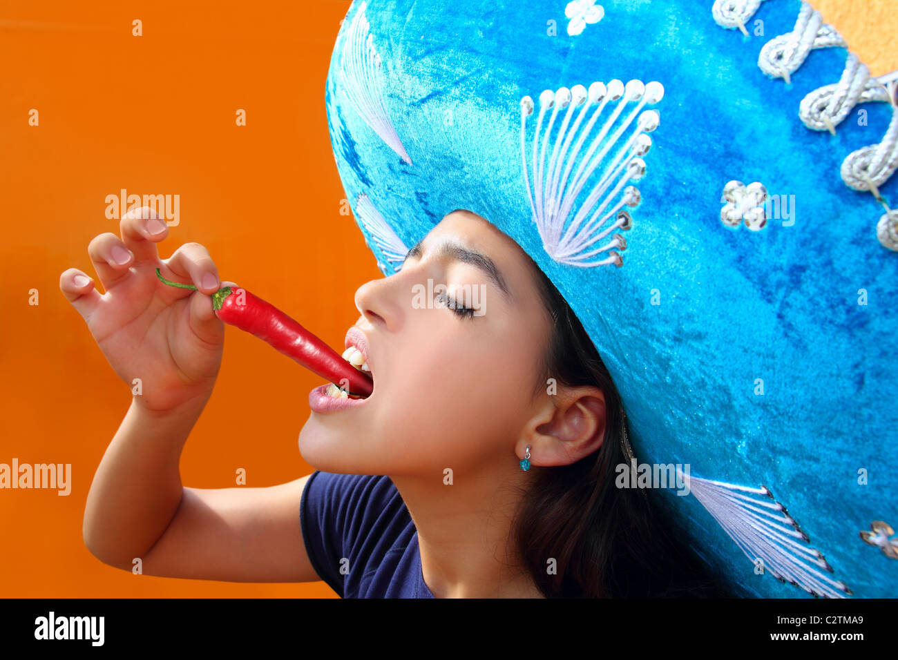 Mexican girl profile eating red hot chili pepper mexican hat Stock Photo