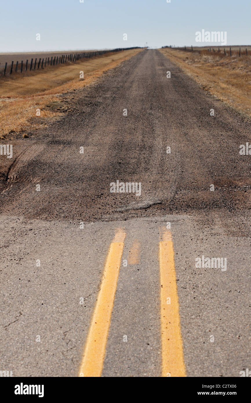the end of the paved road where it turns into a gravel road extending to the horizon Stock Photo