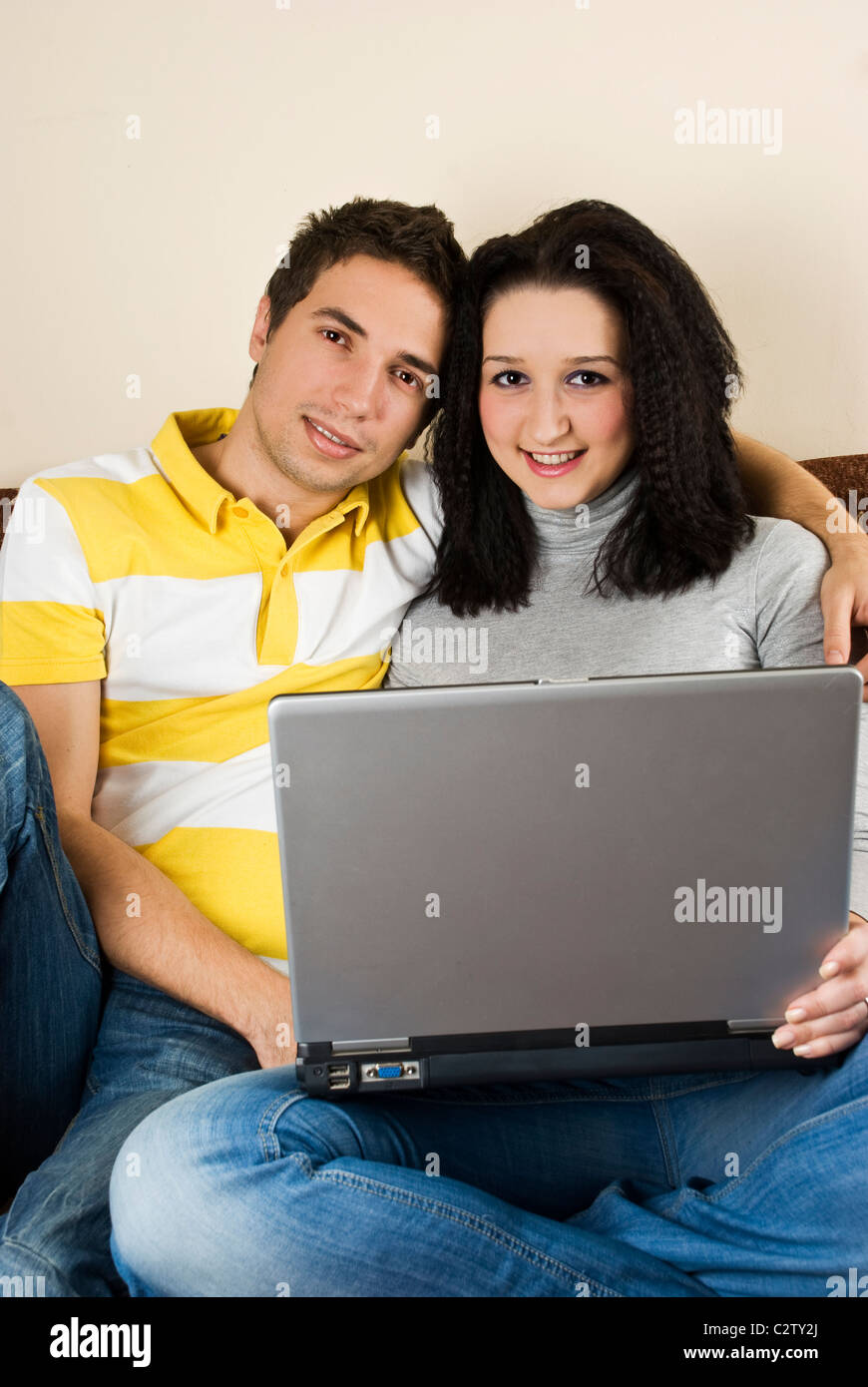 Portrait of young couple sitting on sofa and having fun on laptop Stock ...
