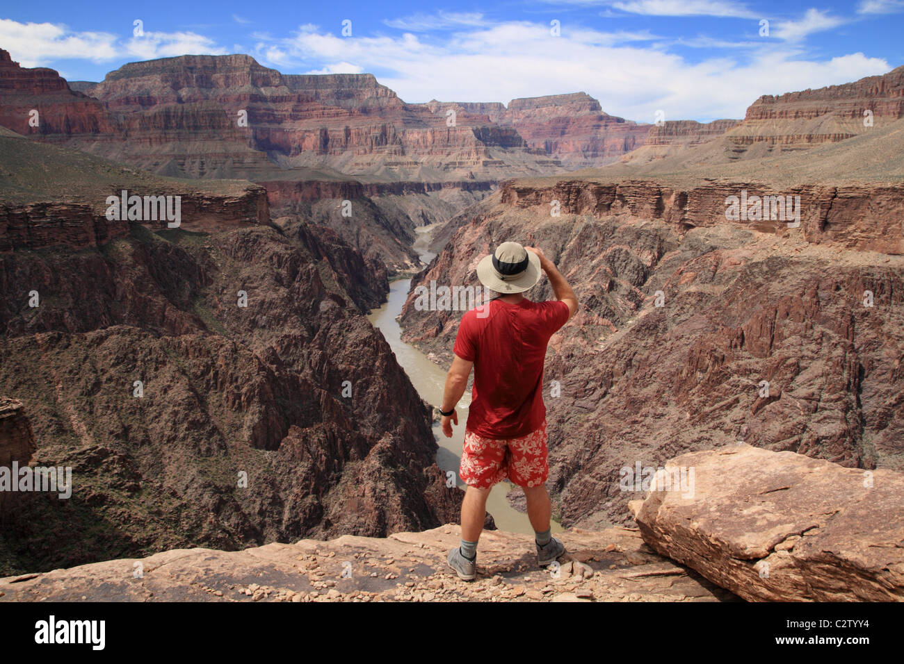 a hiker standing on an overlook in the Grand Canyon looking down into Granite Gorge from the Tonto Plateau Stock Photo