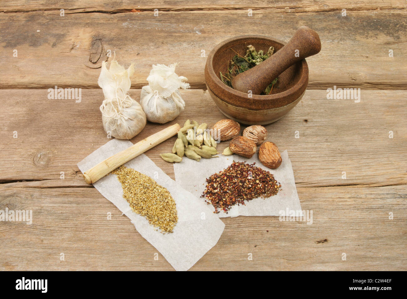 Pestle and mortar with herbs and spices on old weathered wood Stock Photo