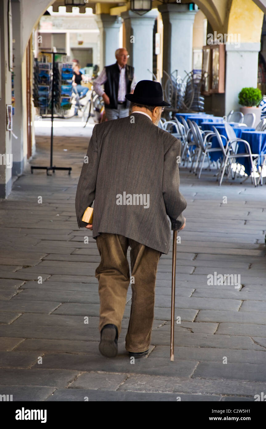 Elderly man walking with a stick in marketplace Stock Photo