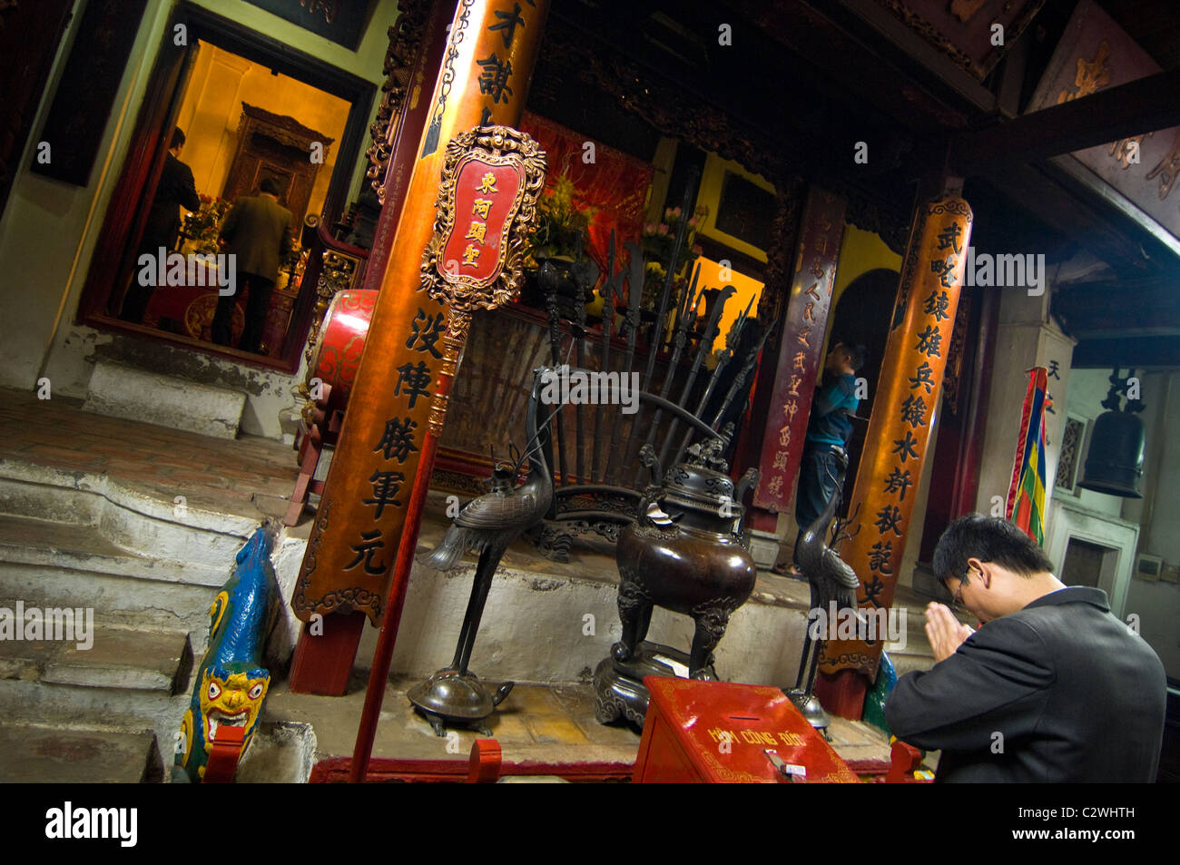 Horizontal view of a Vietnamese man with his head bowed in prayer at Ngoc Son Temple in Hanoi Stock Photo