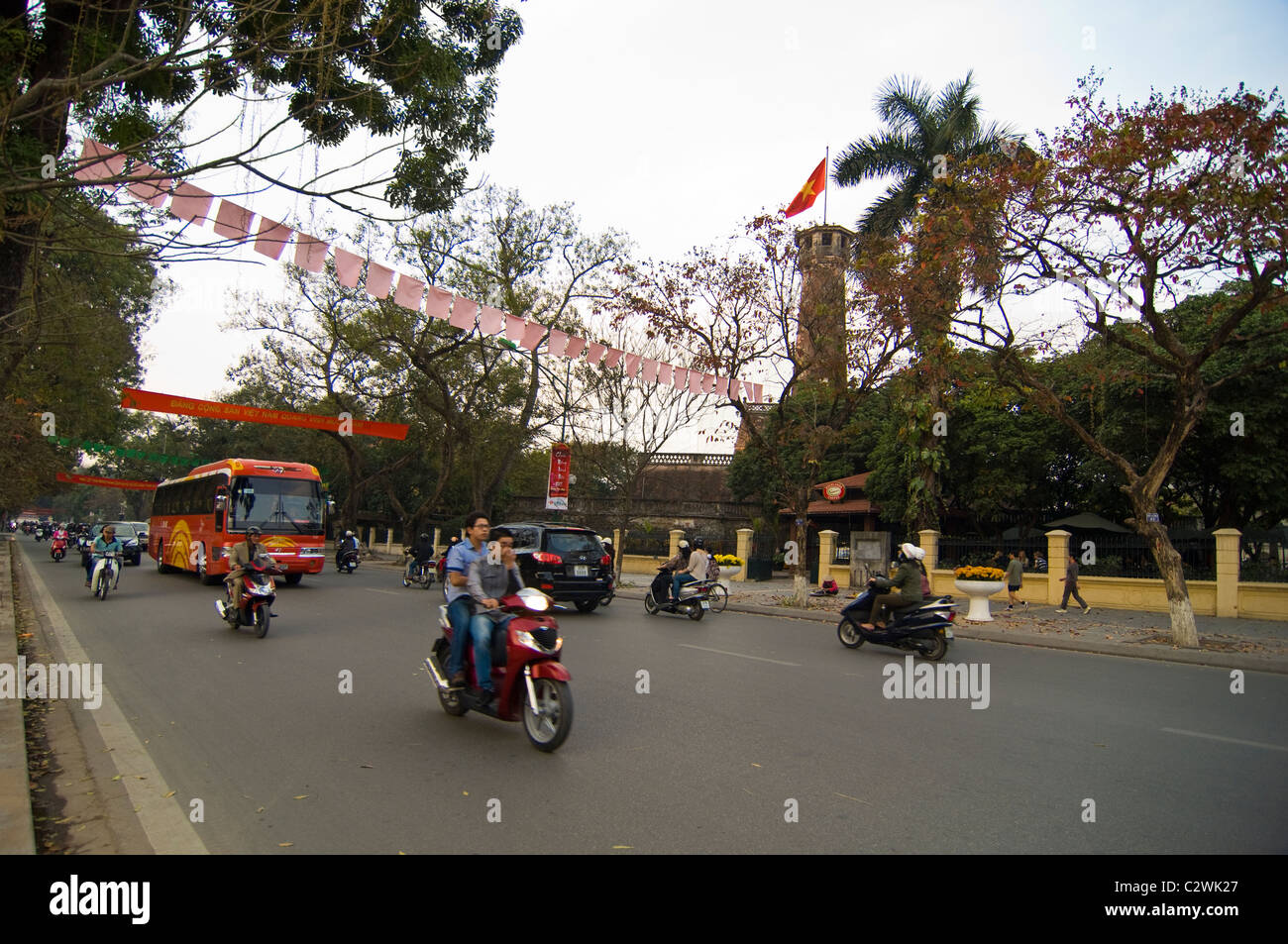 Horizontal wide angle of the Flag Tower of Hanoi (Cột cờ Hà Nội) with mopeds driving passed on Dien Bien Phu. Stock Photo