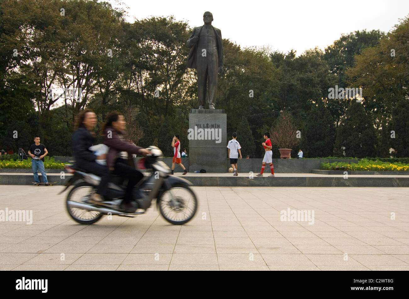 Horizontal wide angle of Lenin's statue in Lenin Park aka Reunification Park (Cong Vien Lenin) with a moped driving passed. Stock Photo