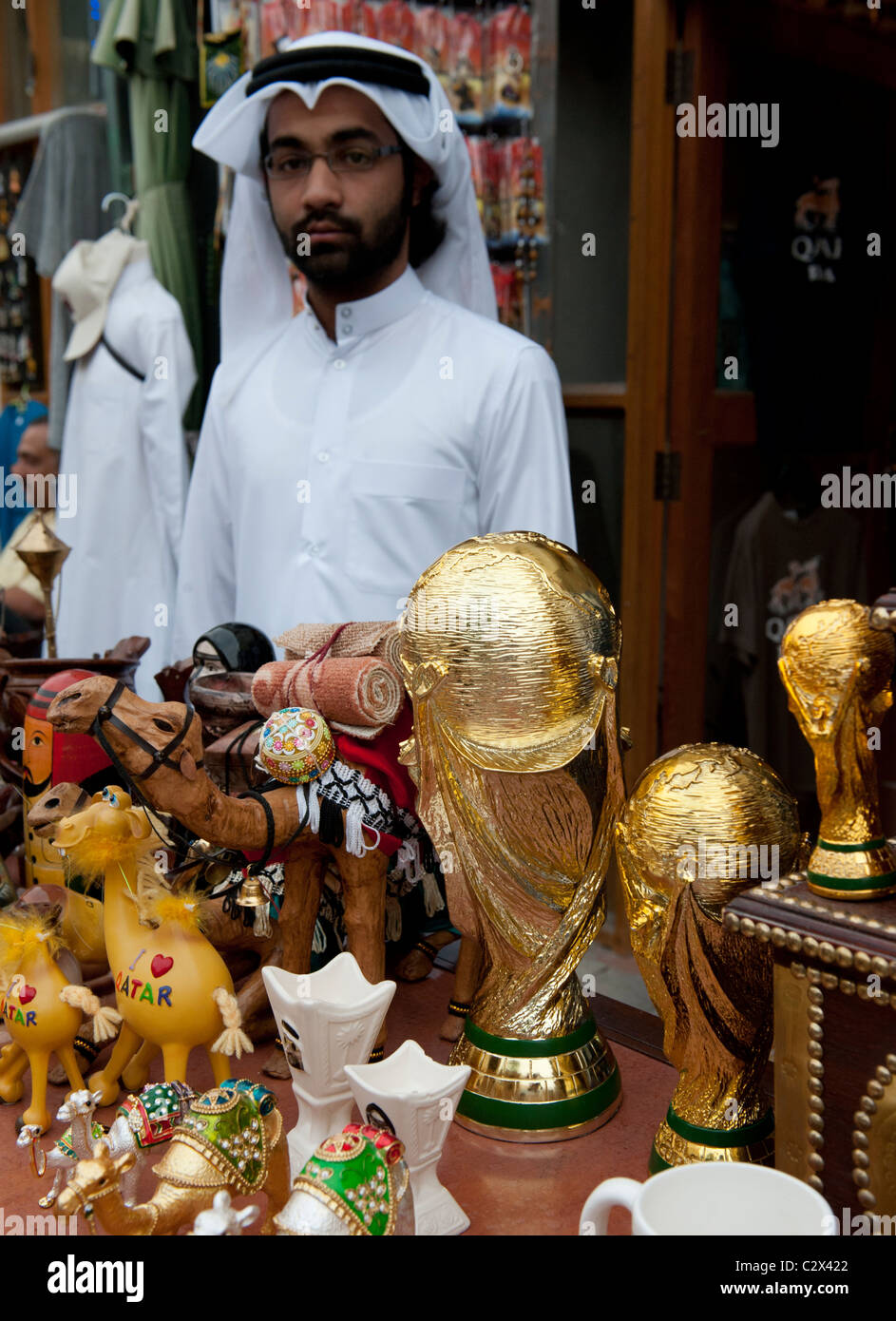 Qatari man selling replica World Cup trophies on tourist market stall in Doha Qatar Stock Photo