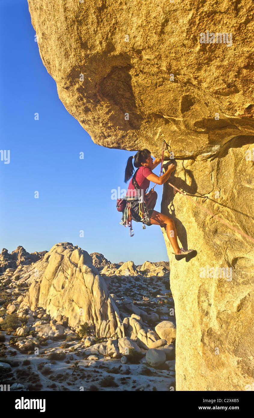 Female rock climber struggles for her next grip on a challenging ascent