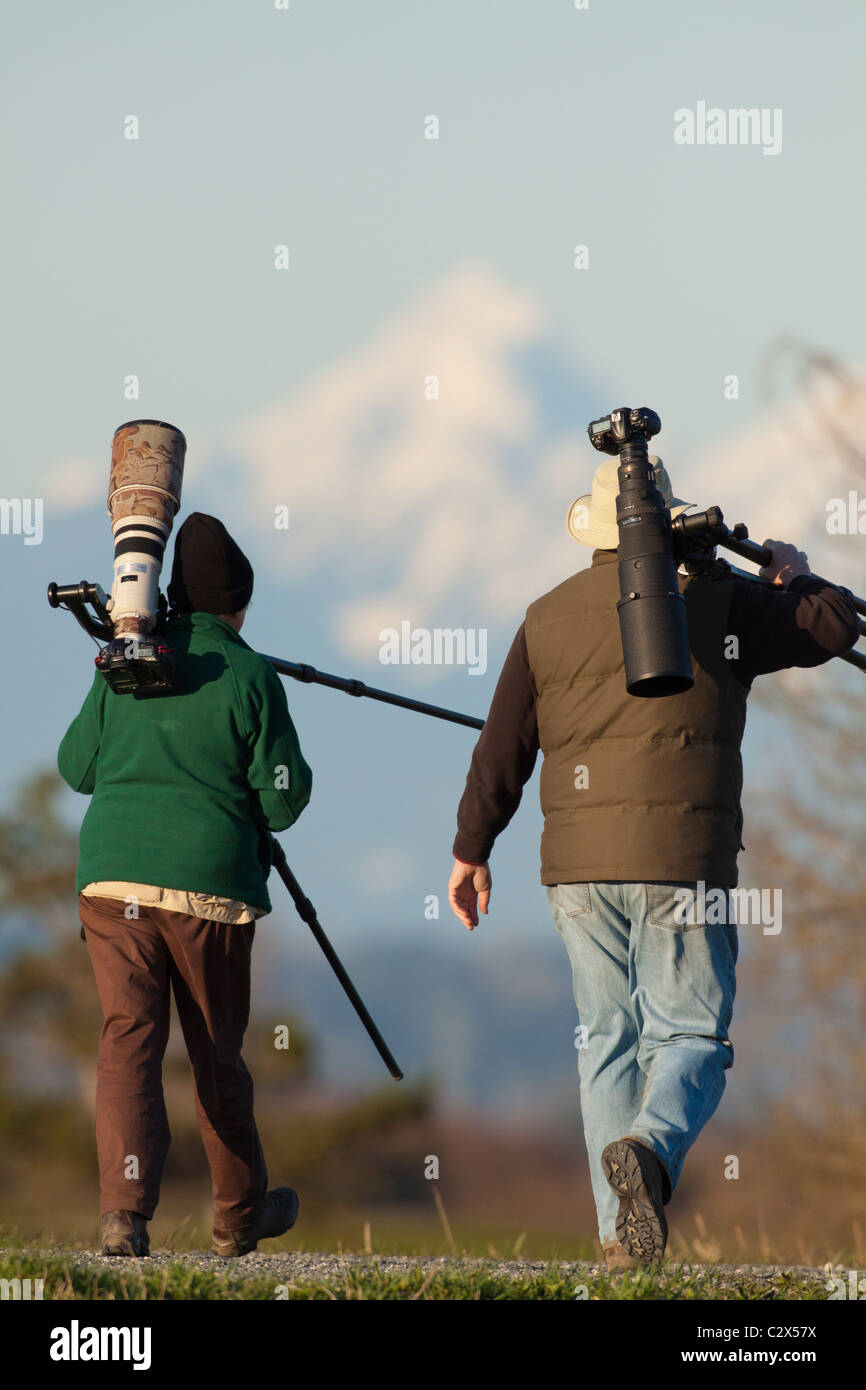 Photographer's walking on dyke at edge of marsh-Boundary Bay, Vancouver, British Columbia, Canada. Stock Photo