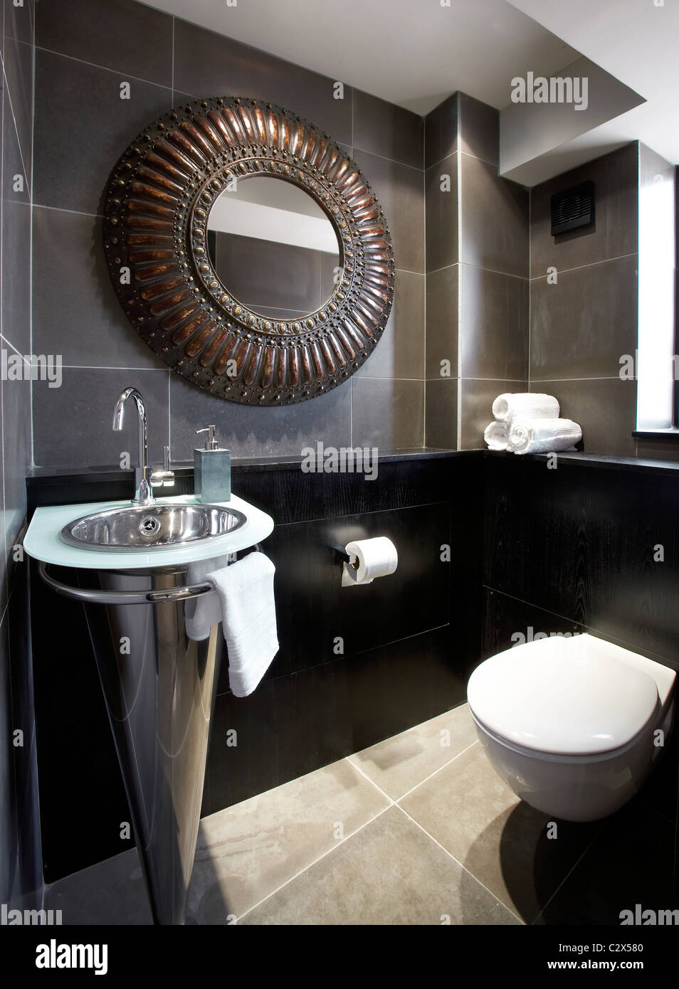 Dark tiles toilet tapered steel wash basin copper mirror Stock Photo
