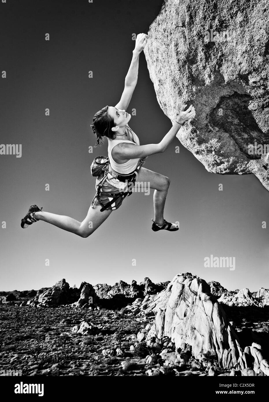 Female rock climber struggles for her next grip on a challenging ascent. Stock Photo