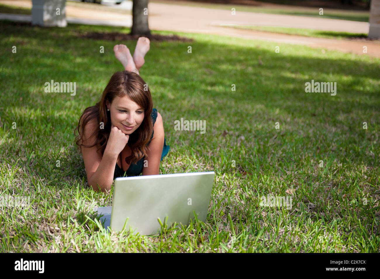 Smiling young woman lying on stomach, hand under chin, works on