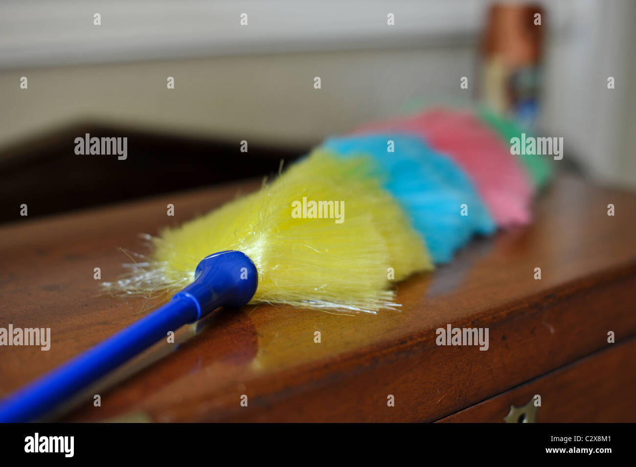 Brightly coloured feather duster lying on a polished wooden Victorian