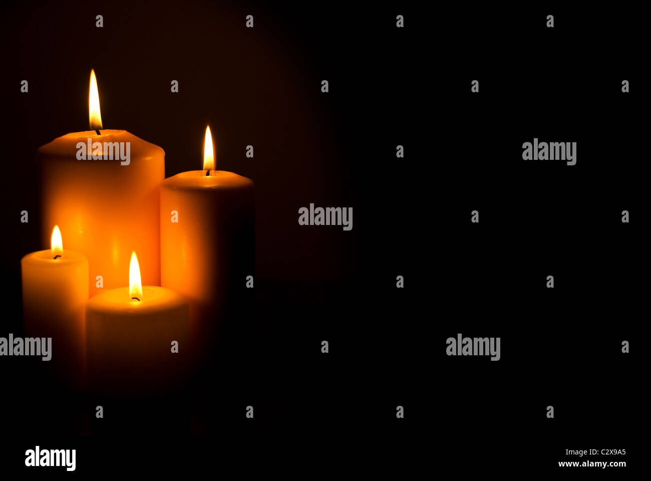 Group of four candles lights in a side in darkness with copy space for