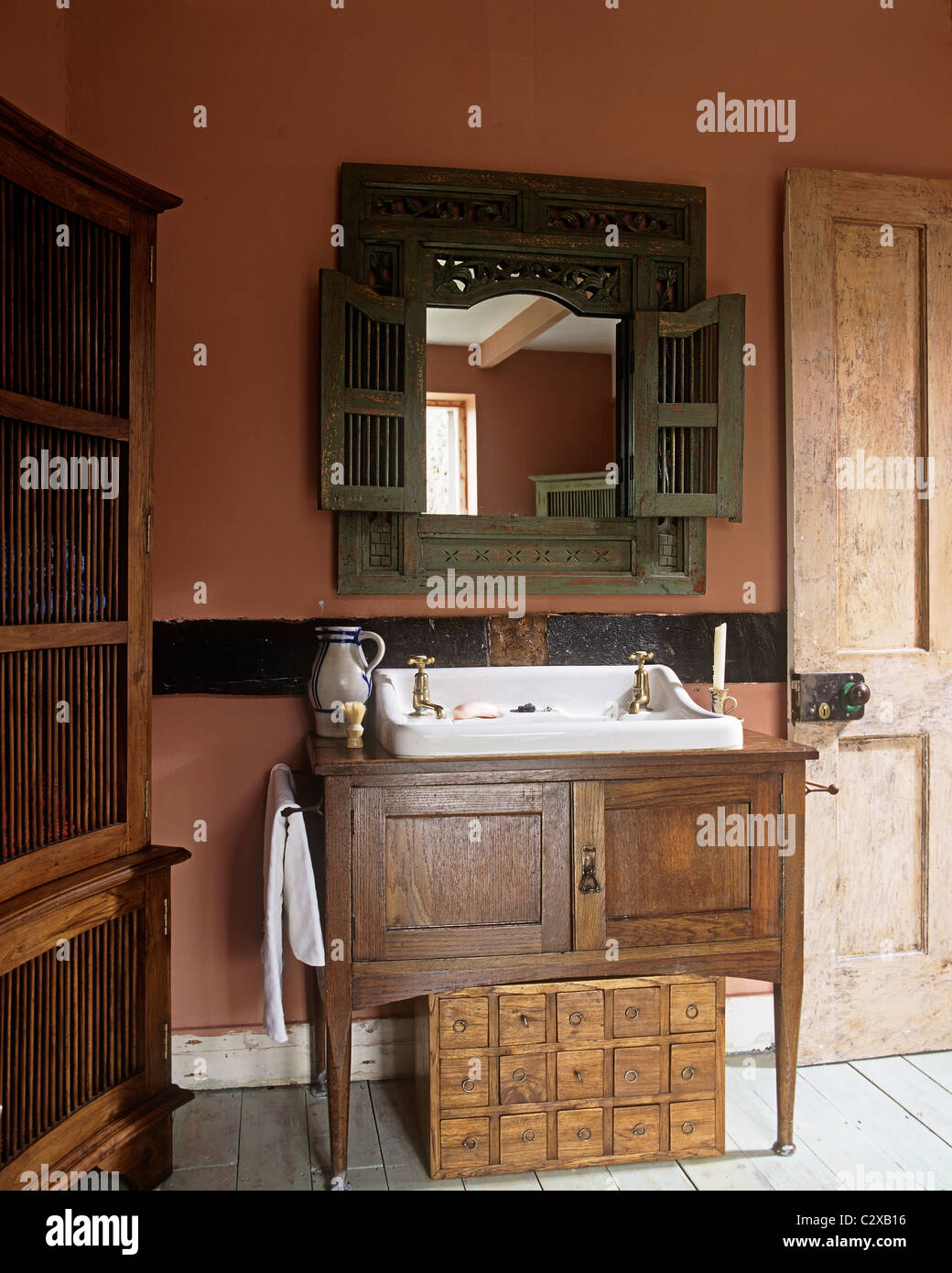 Washbasin in wooden cupboard in red, country style bathroom Stock Photo