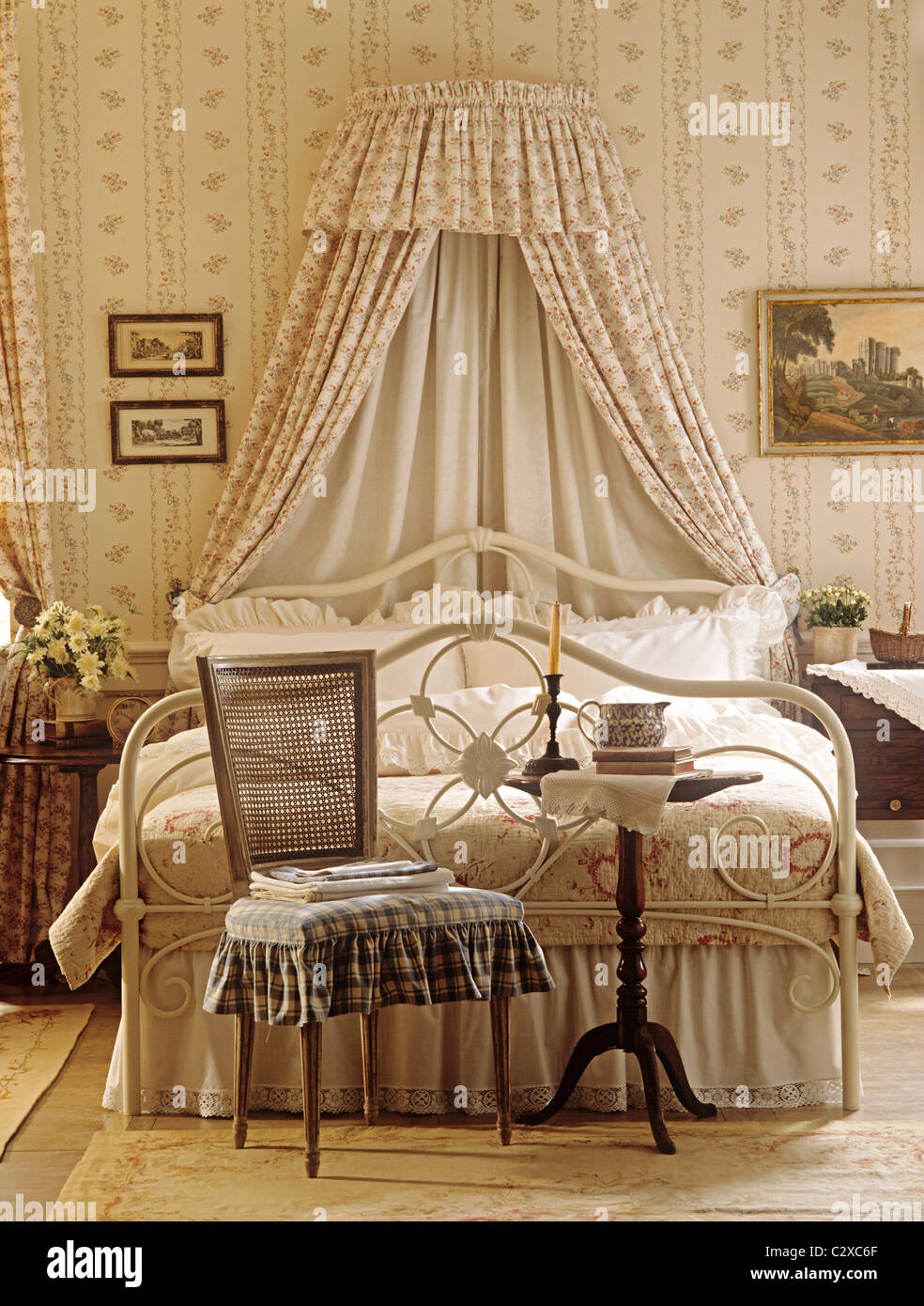 Wrought iron double bed with corona in pretty floral bedroom Stock