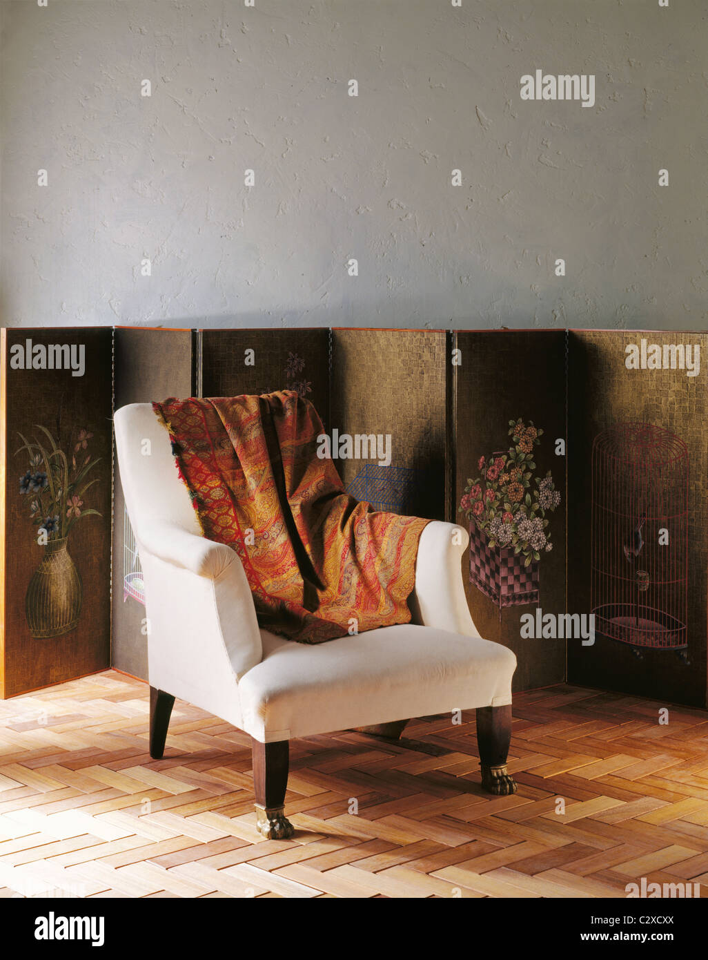 White fabric covered armchair with orange and red throw draped over arm