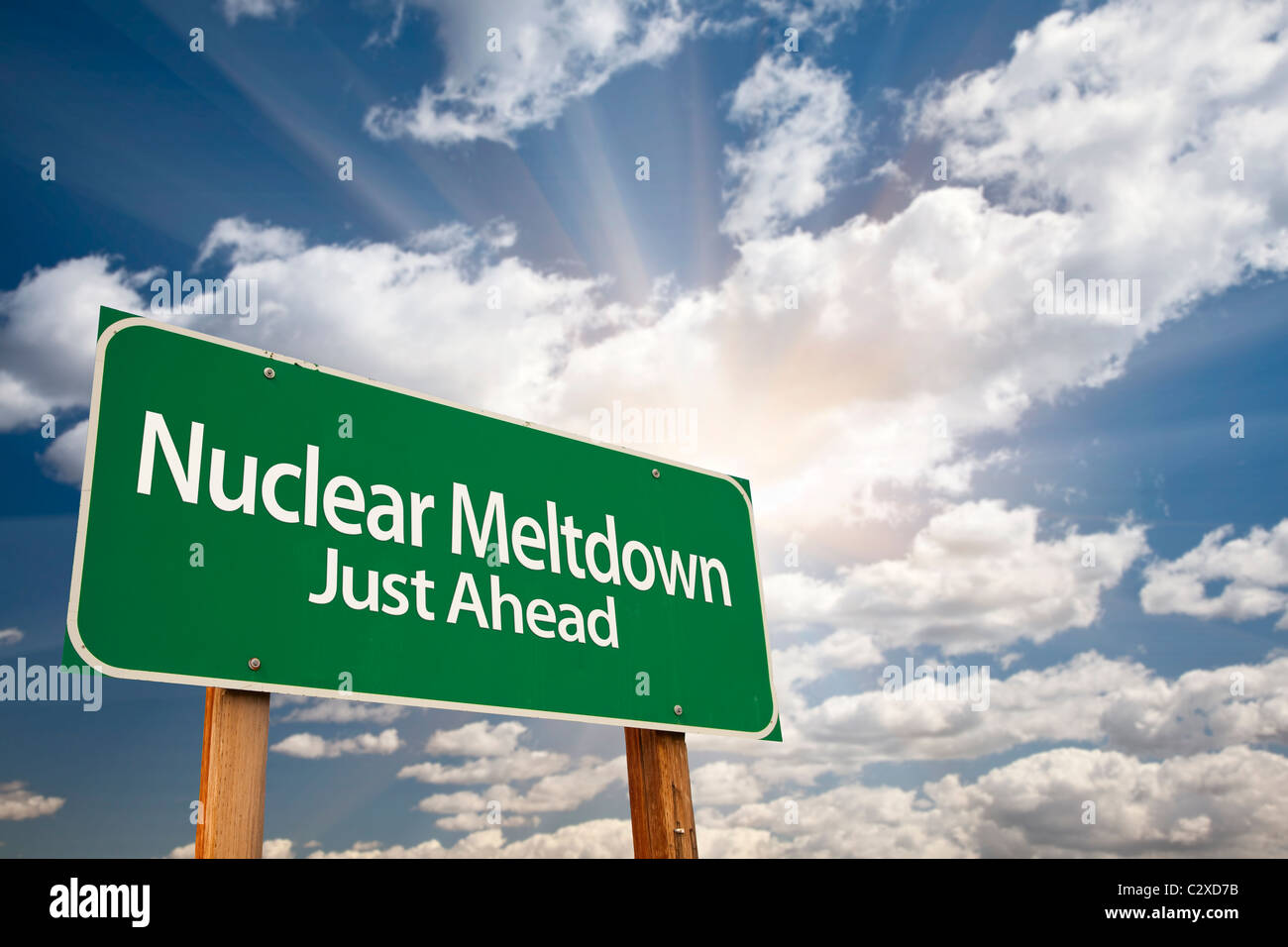 Nuclear Meltdown Green Road Sign with Dramatic Clouds, Sun Rays and Sky. Stock Photo