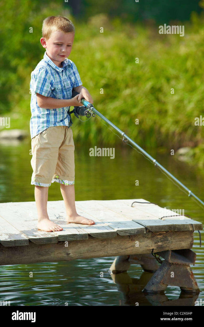 Fishing kid. Boy with spinner at river. Kid at jetty with rod