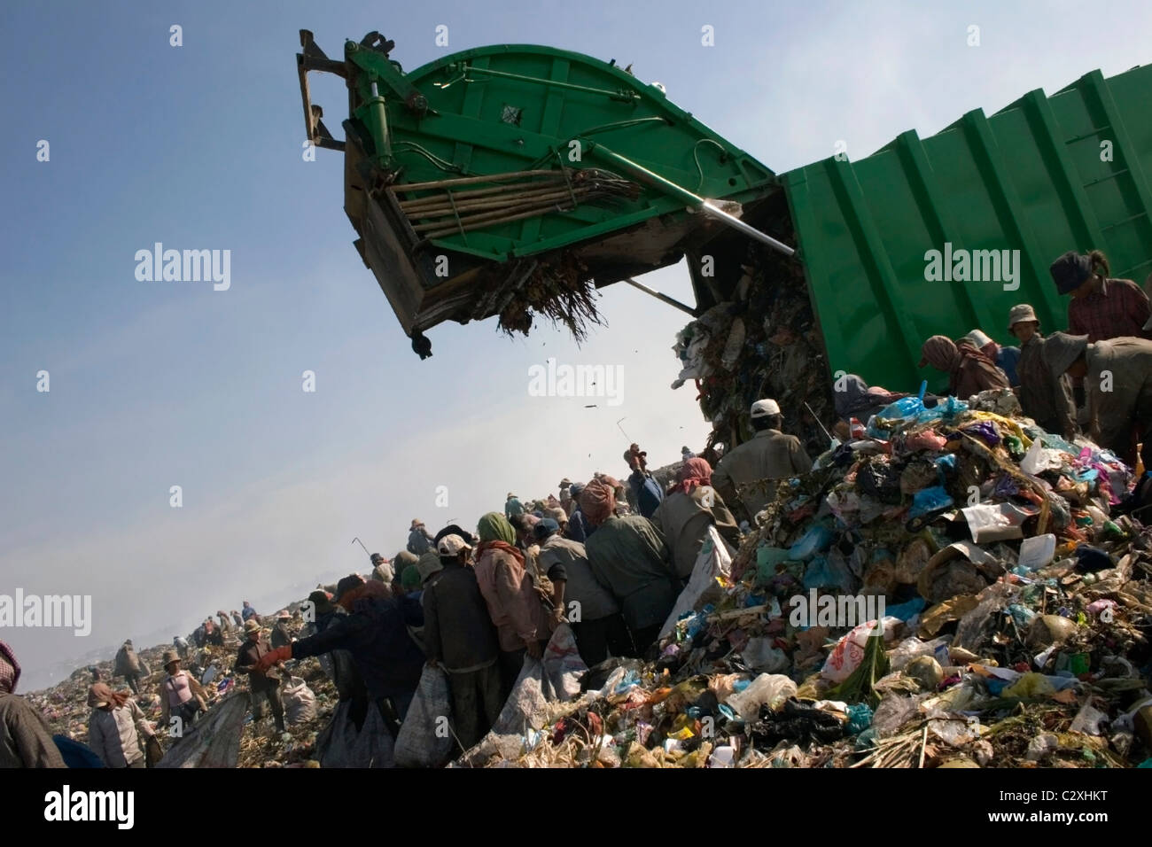 Trash workers are collecting recyclable material at a polluted garbage dump in Cambodia. Stock Photo