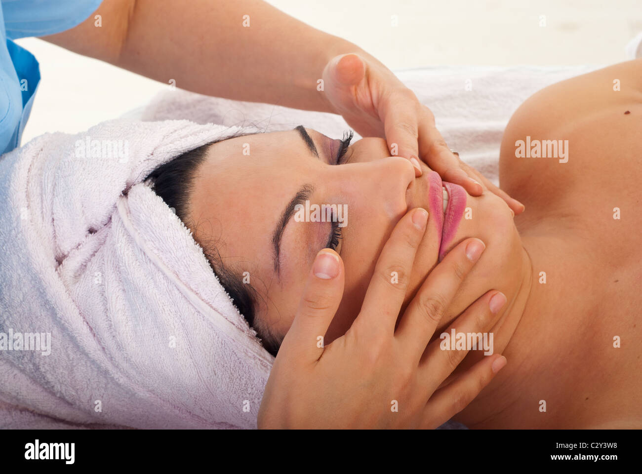 Beautician giving facial massage to a beauty woman in a spa salon Stock Photo