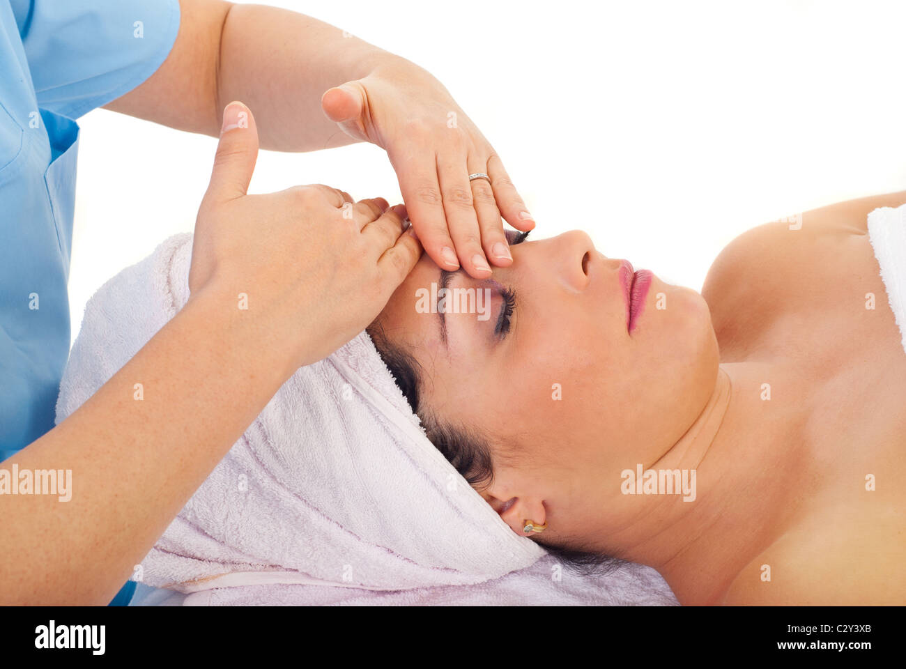 Beautician giving facial massage to a beautiful woman at spa resort Stock Photo
