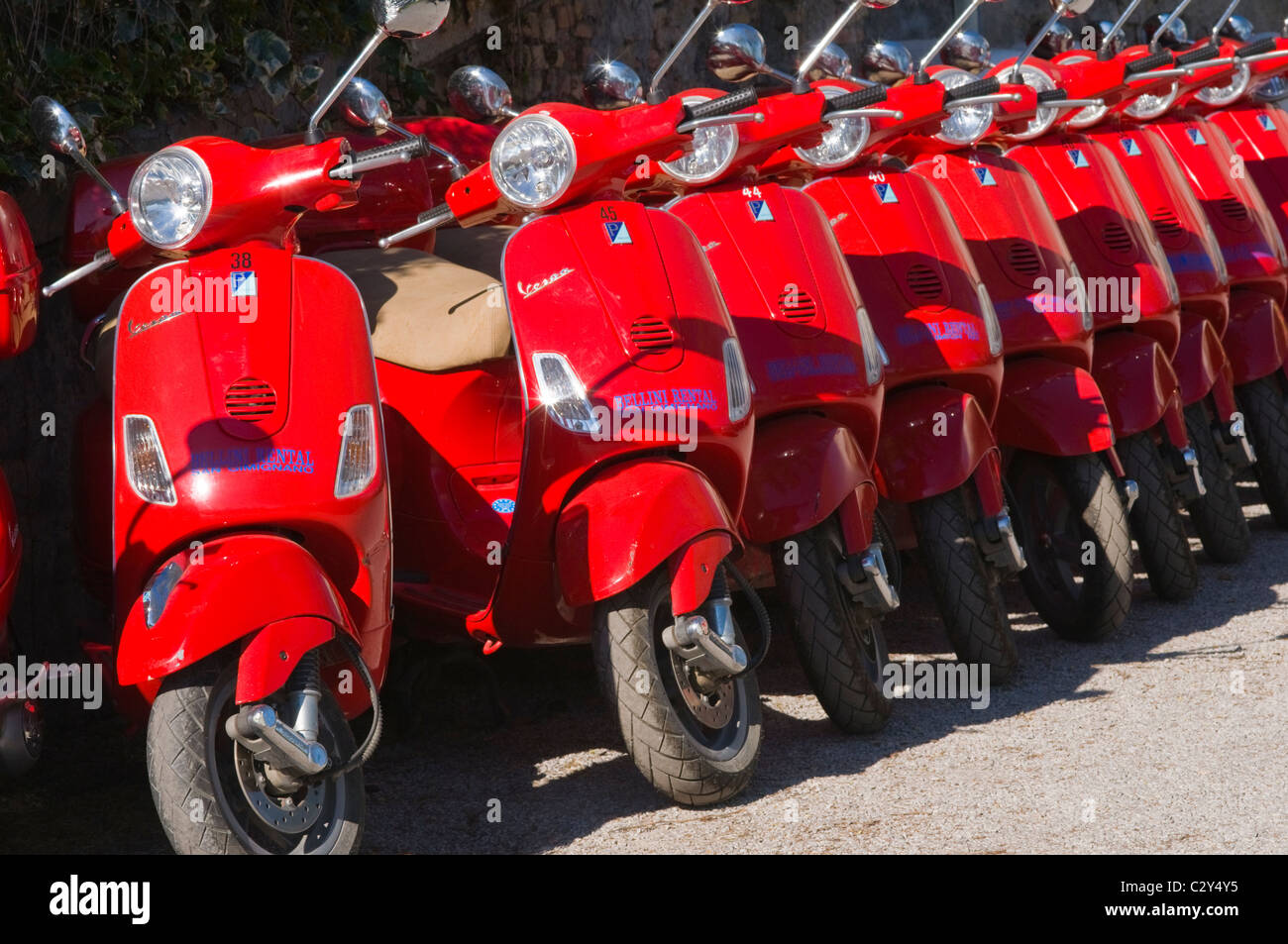 A Row of Bright Red Vespa Scooters Outside a Rental Company in Italy
