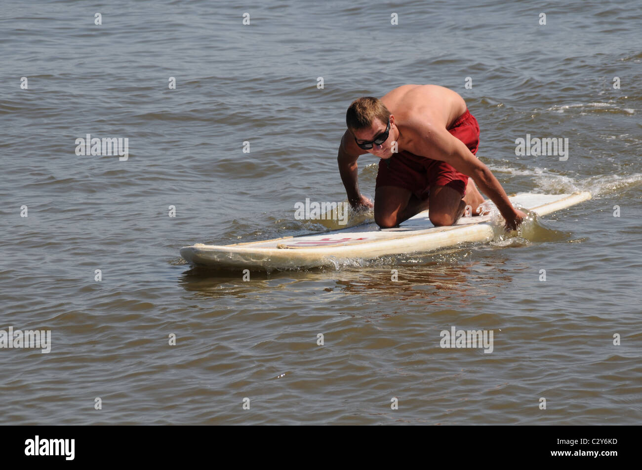 Young man on a surf board at Sandy Point Beach in Maryland Stock Photo
