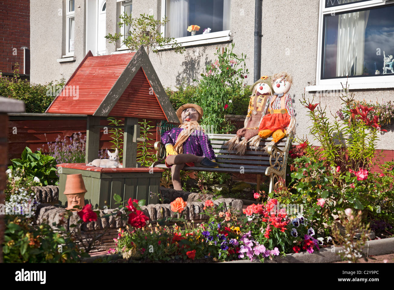 Scarecrows beside a wishing well in a garden, as an entry in the West Kilbride Scarecrow Festival 2010. Stock Photo