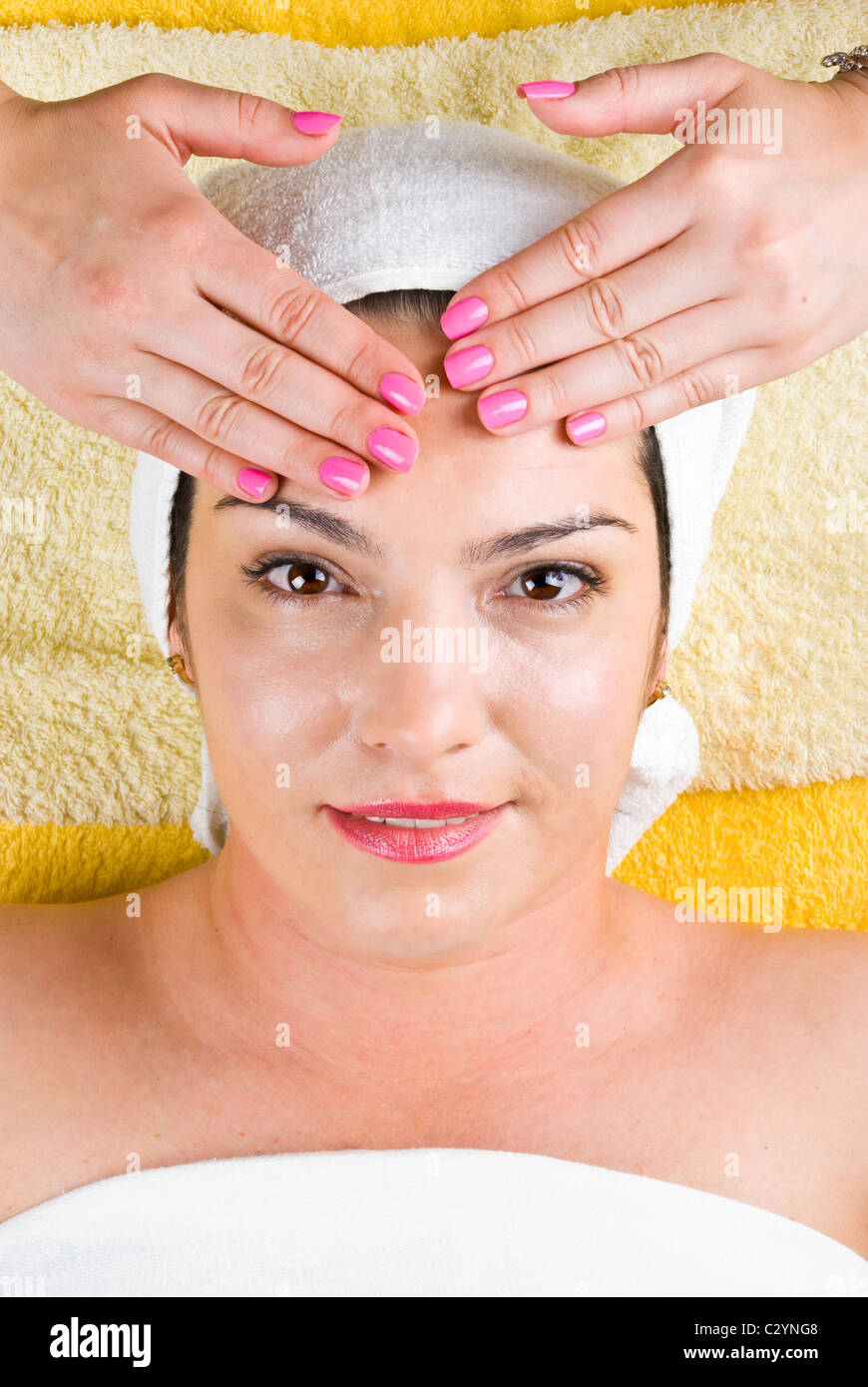 Attractive woman getting a facial massage at spa salon and looking happy Stock Photo