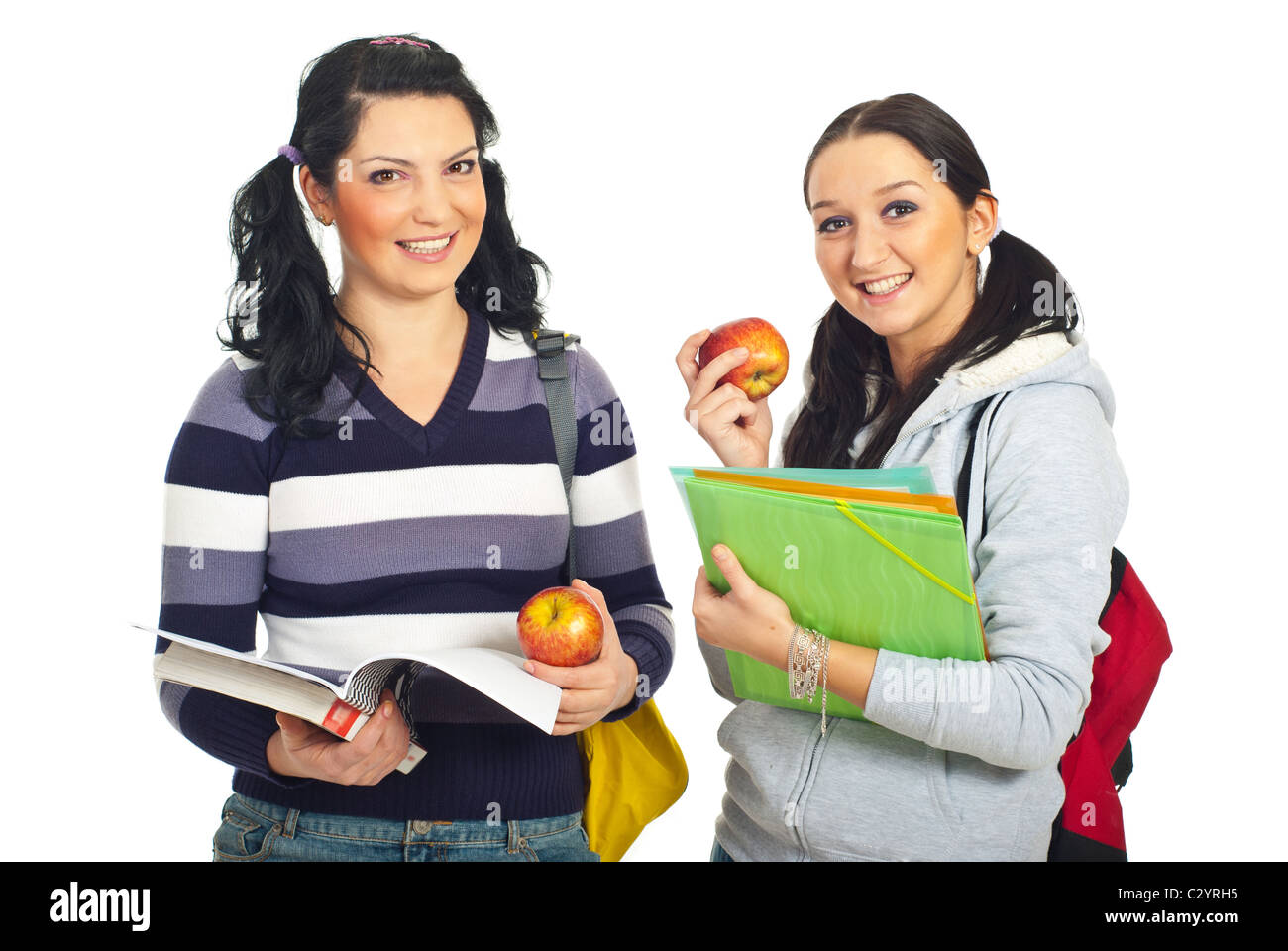 Two pretty smiling students females holding apples and books isolated ...