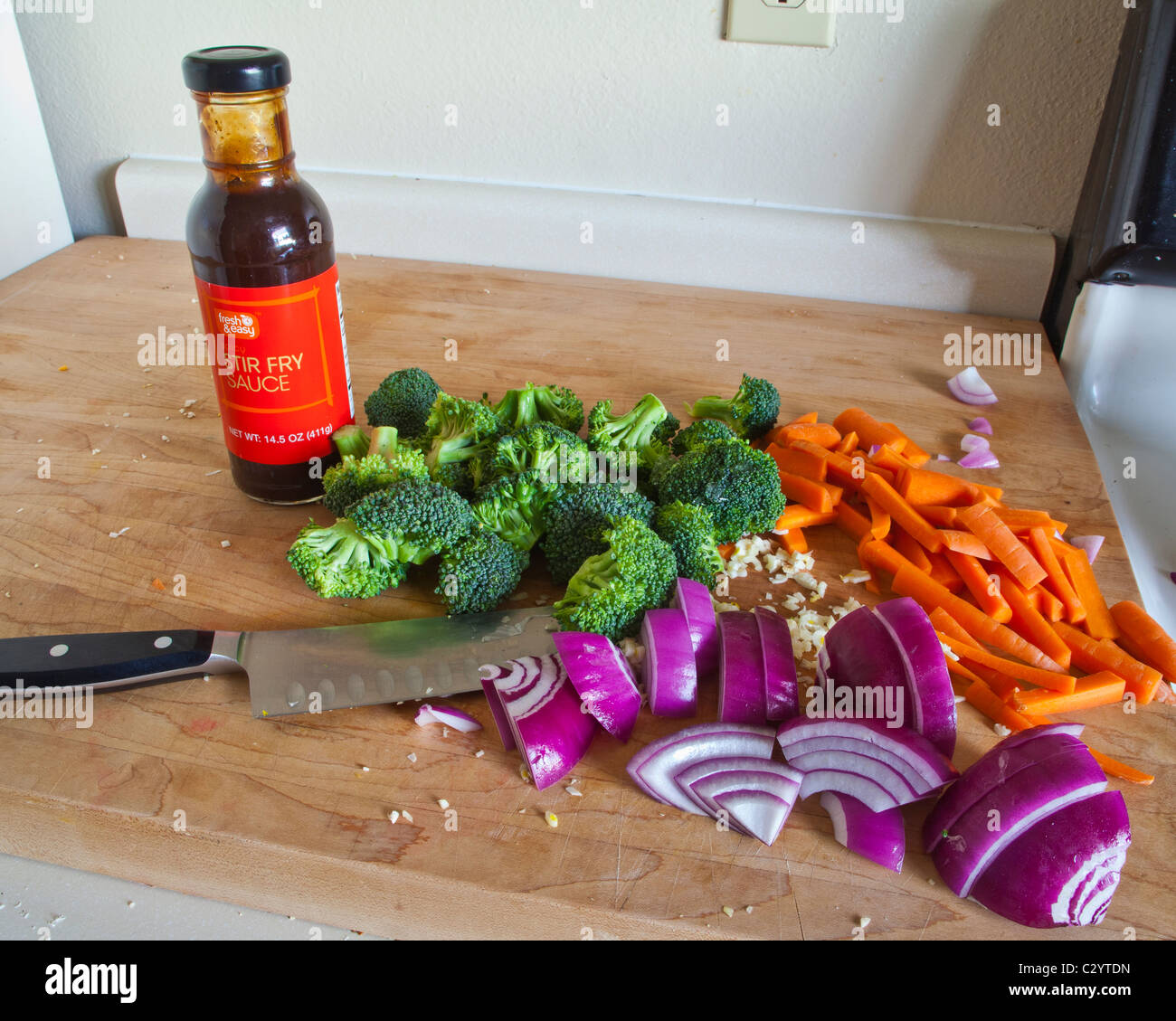 Cut up vegetables ready to be stir fried with a bottle of stir fry sauce Stock Photo