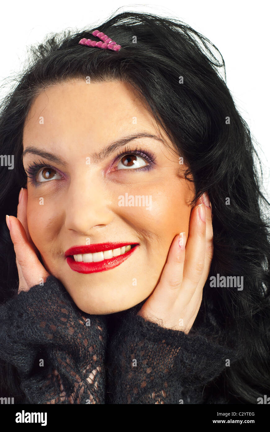 Close up of beautiful woman with red lipstick looking up and dreaming with open eyes and holding palms on her face Stock Photo