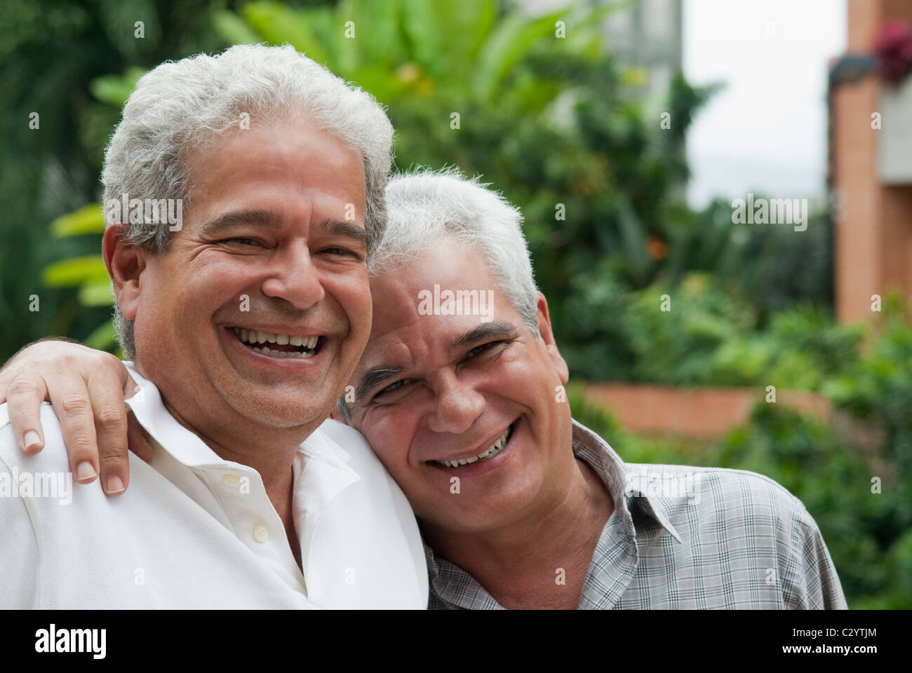 Smiling Hispanic men hugging Stock Photo