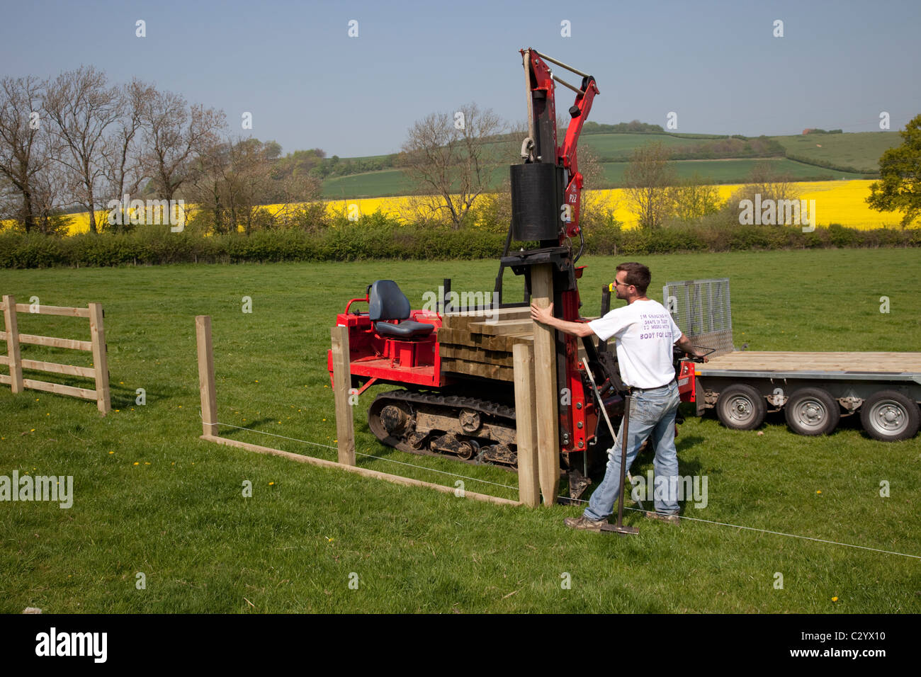 Workman straightening timber fence post wiith dedicated Kubota P22 Protech Post Rammer Cotswolds UK Stock Photo