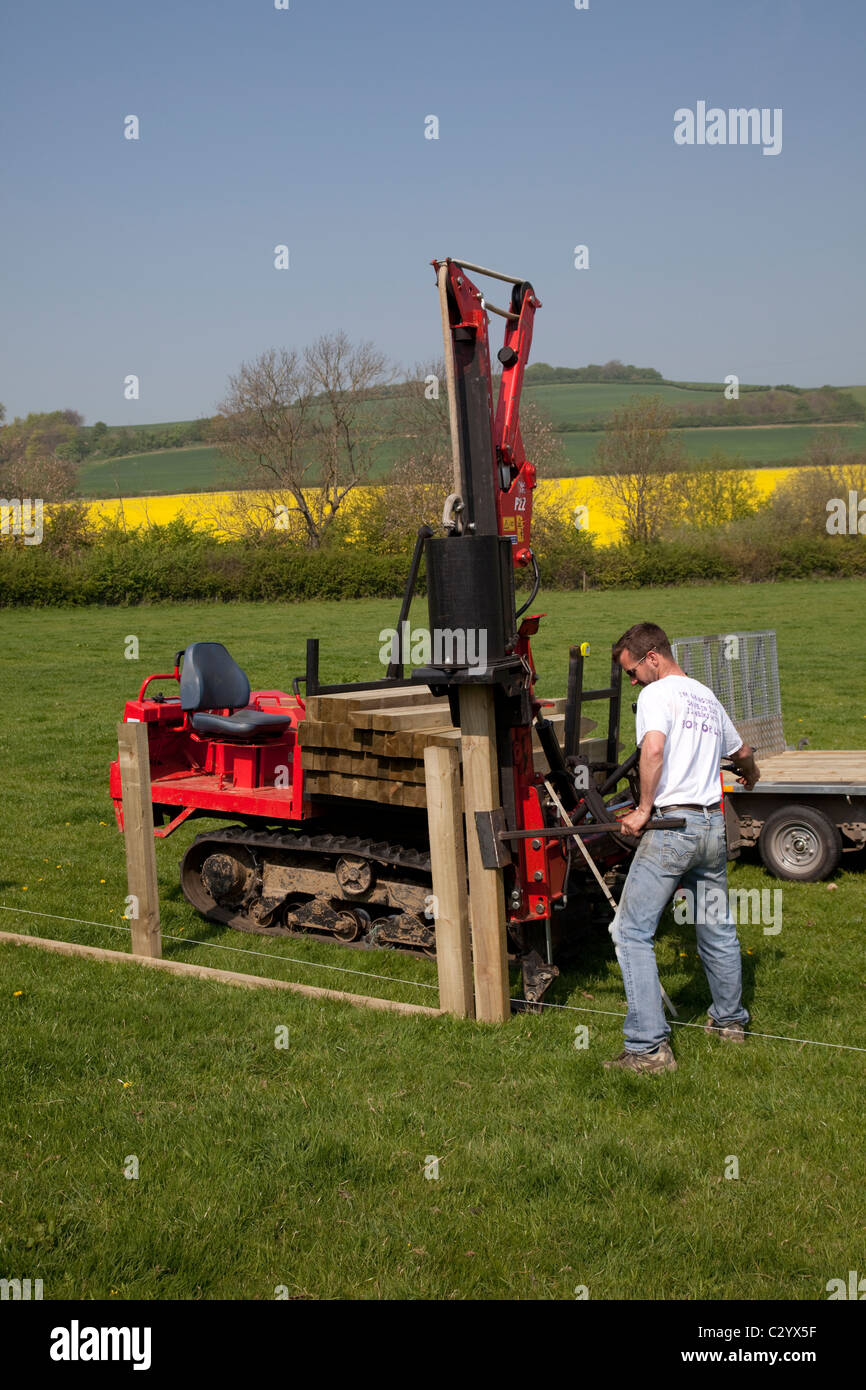 Workman straightening timber fence post wiith dedicated Kubota P22 Protech Post Rammer Cotswolds UK Stock Photo