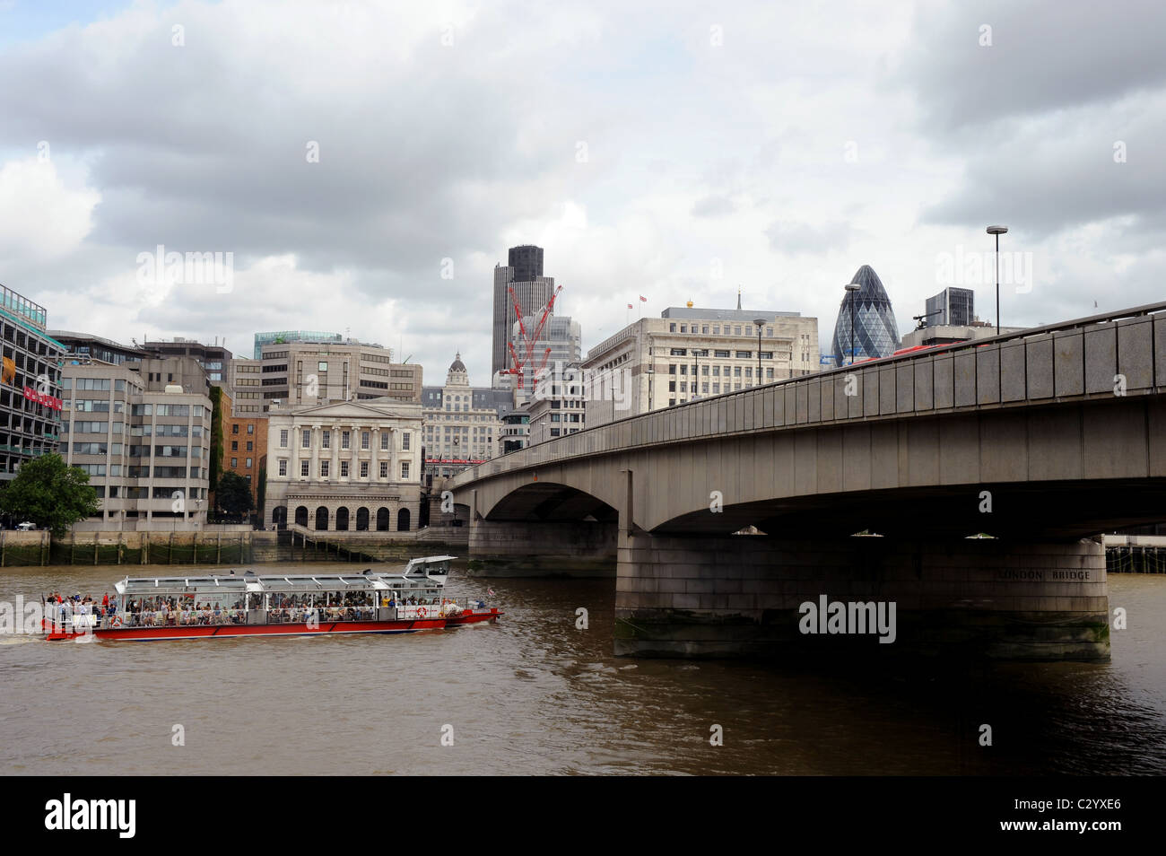 A sightseeing boat going under London Bridge, the City in the background. Stock Photo