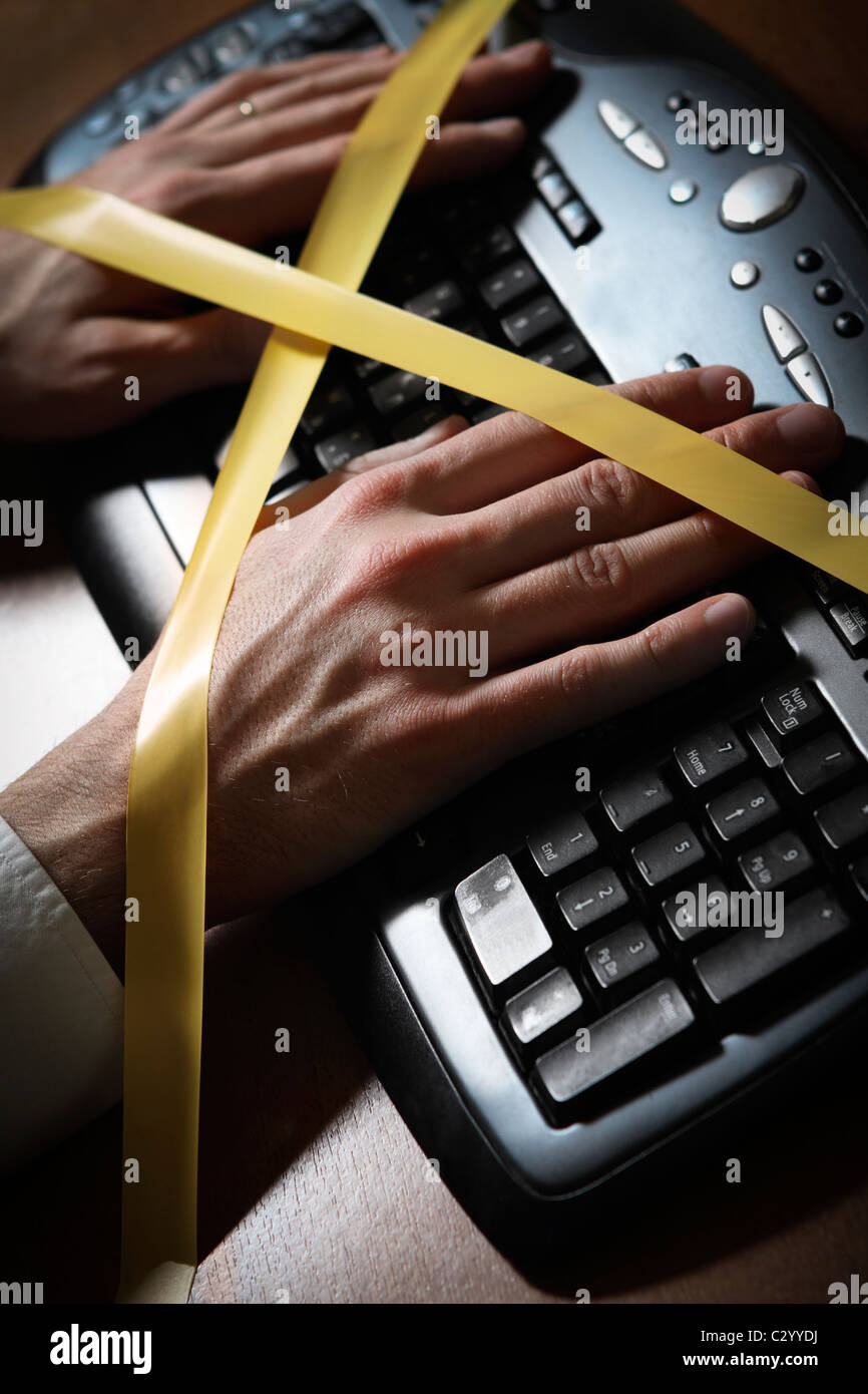Closeup of a man's hand with duct tape typing at a computer keyboard