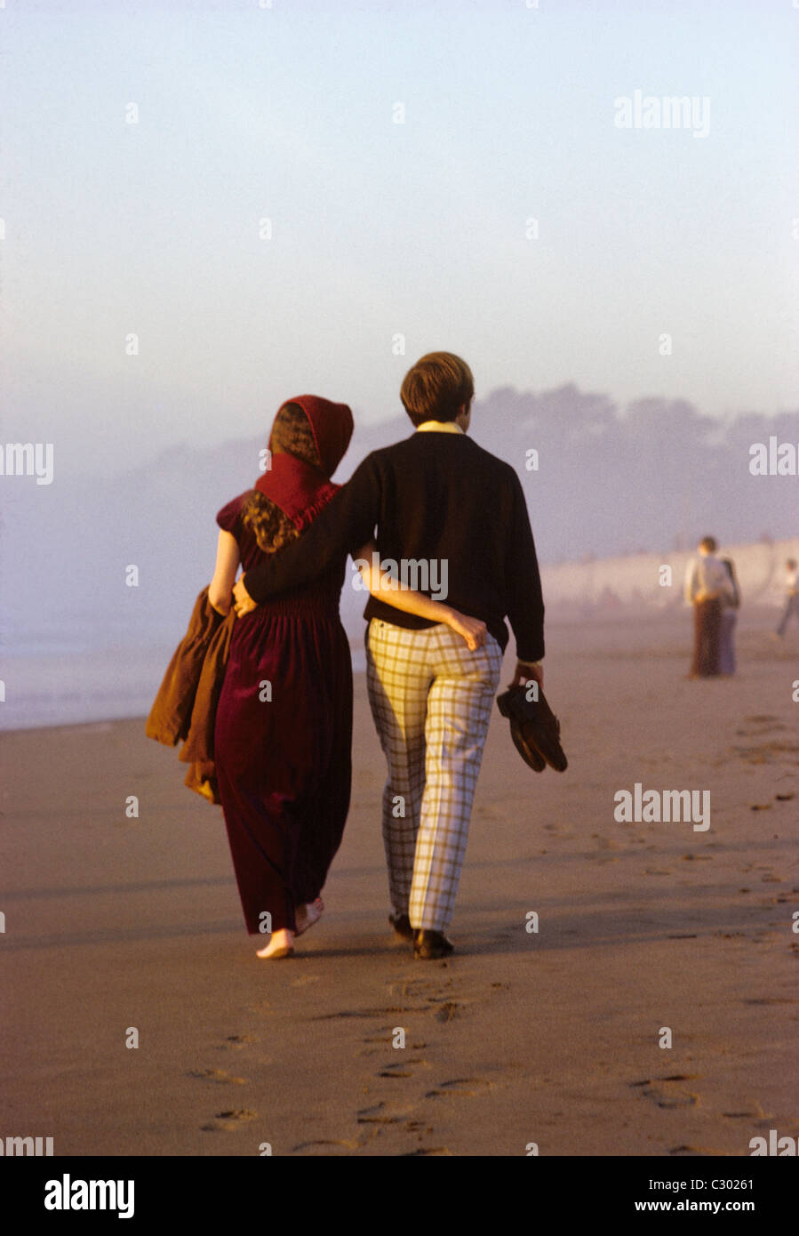 two young lovers stroll barefoot in the sand on ocean beach San Francisco Stock Photo
