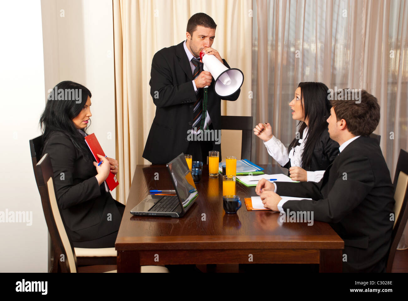Furious chief shouting in megaphone to his employees at meeting Stock Photo