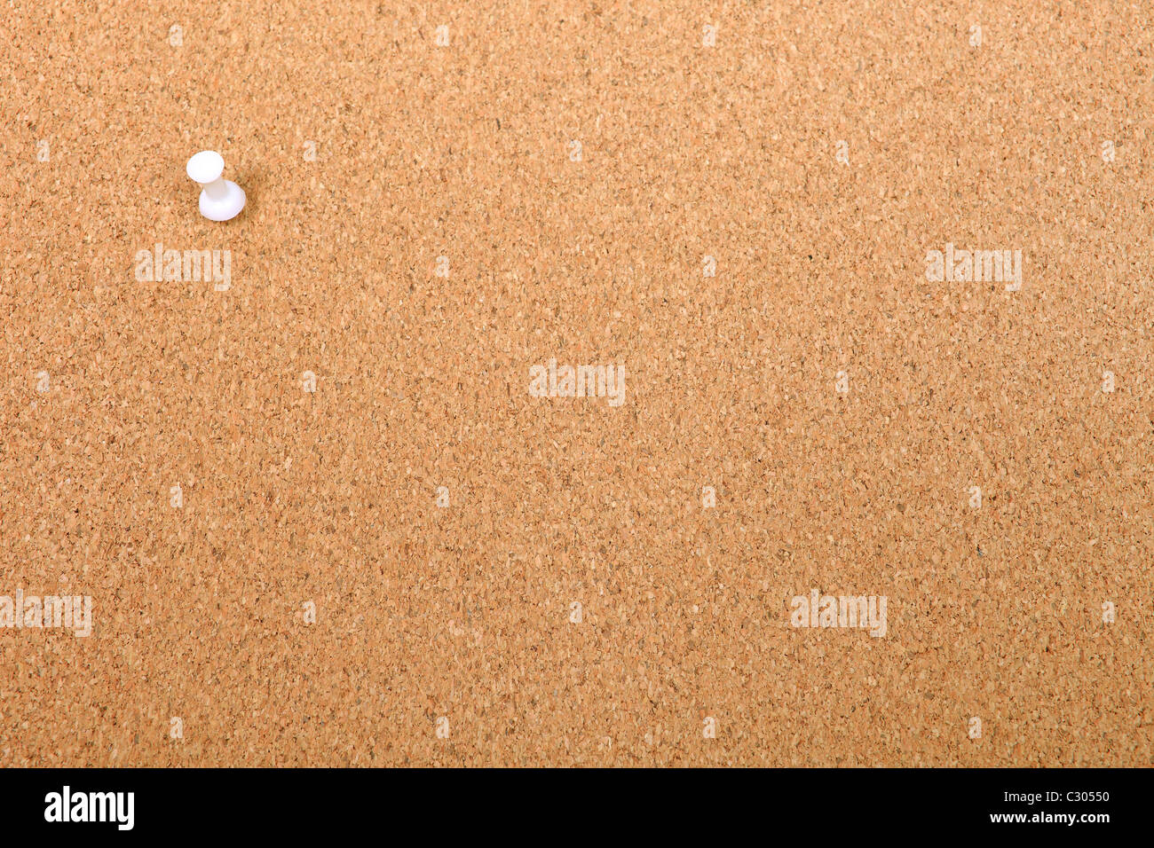 White thumbtack attached to cork message board. Good as background or backdrop. Stock Photo